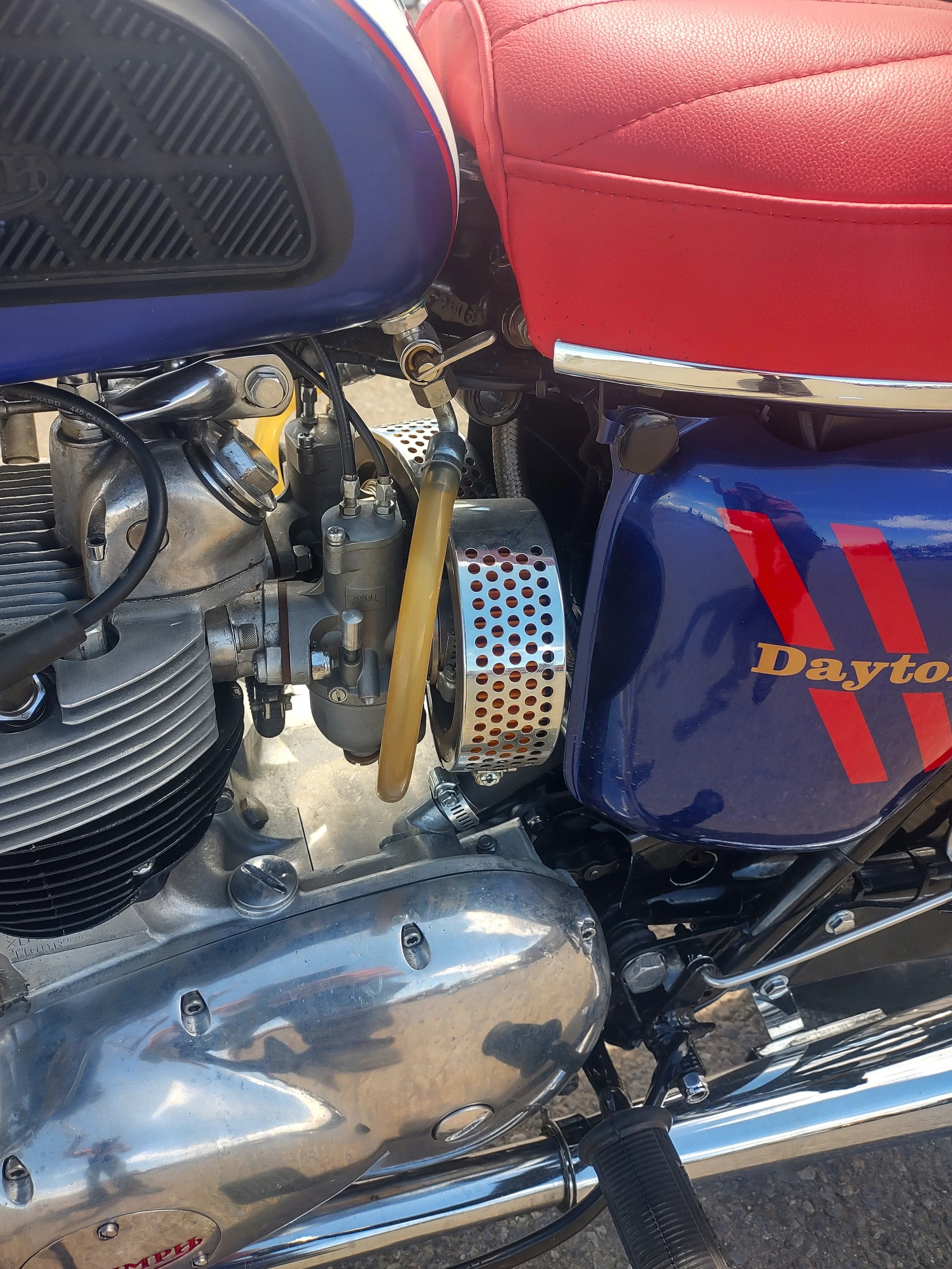Close-up of a vintage Daytona motorcycle engine and part of the red and blue fuel tank with the Daytona logo.