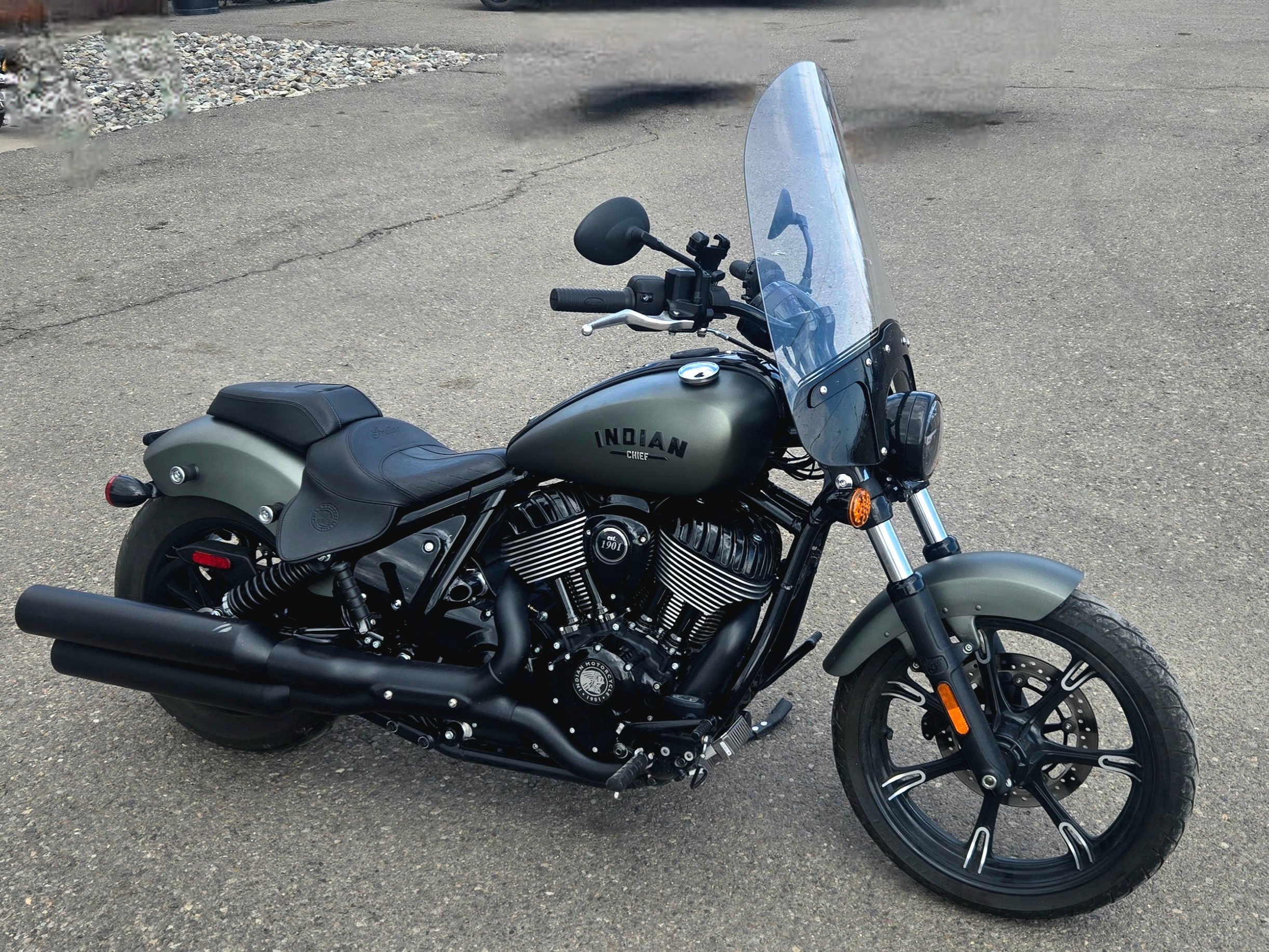 Black and gray Indian motorcycle with a windshield parked on a paved surface.