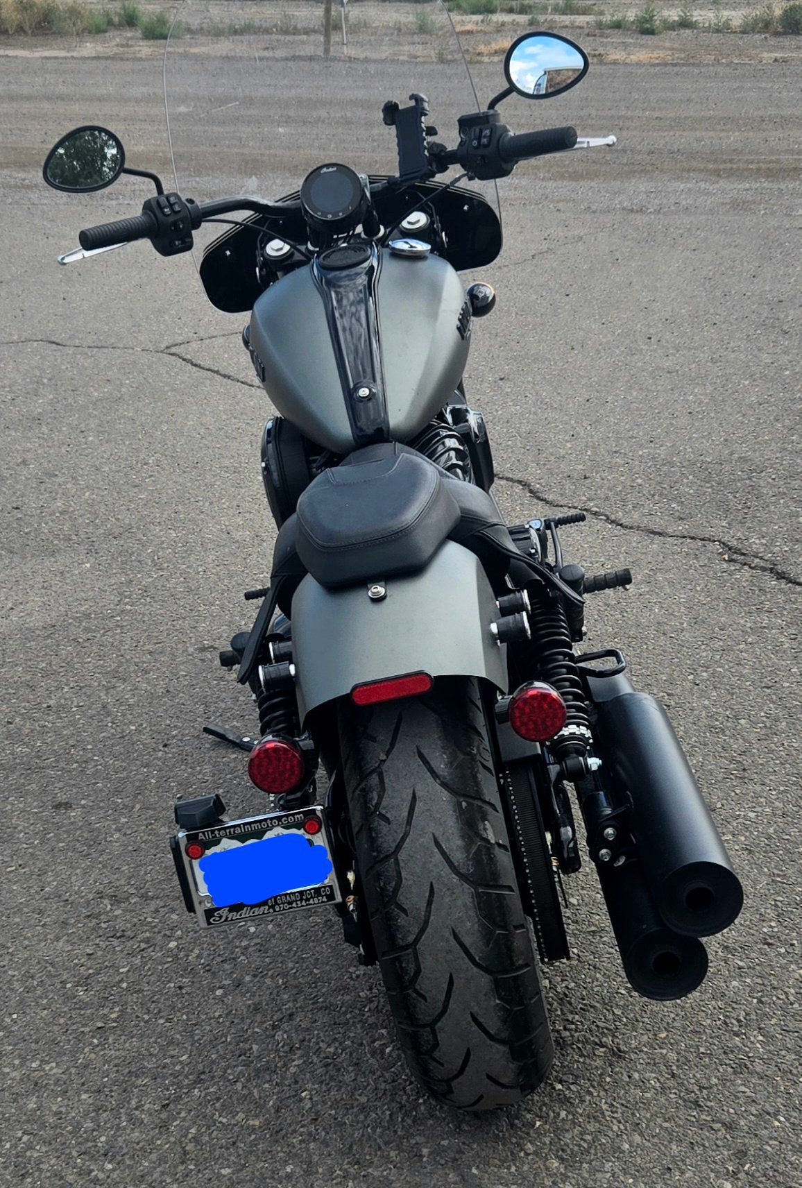 A silver and black motorcycle parked on an asphalt surface, viewed from the rear.