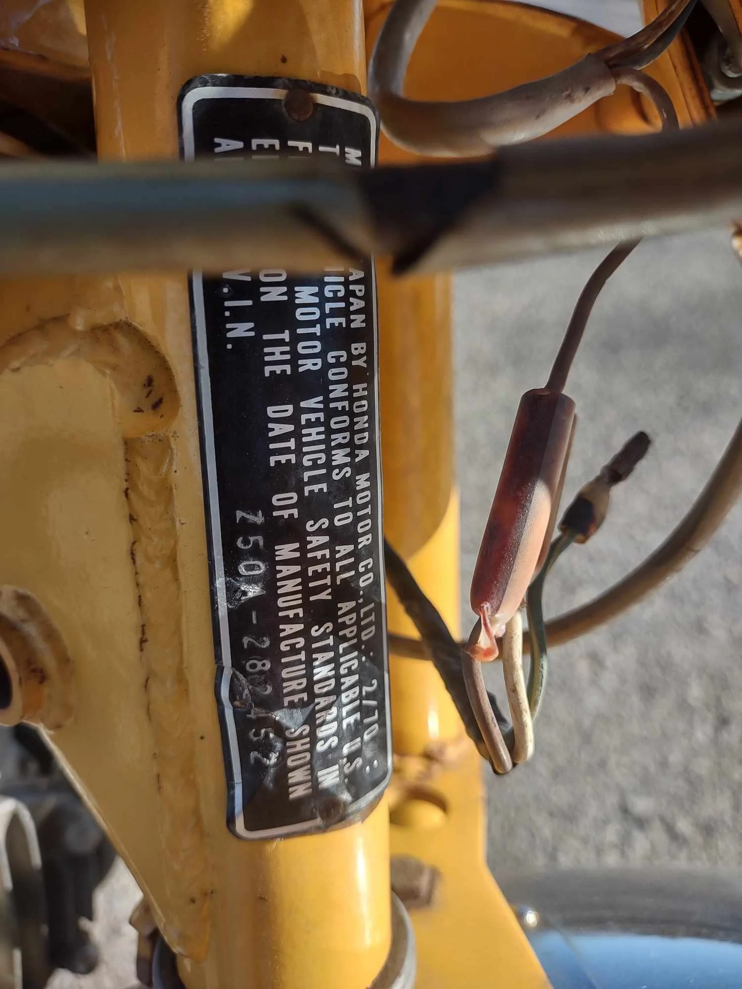 Close-up of a yellow machinery or vehicle part with a black and white safety and manufacturing label attached.