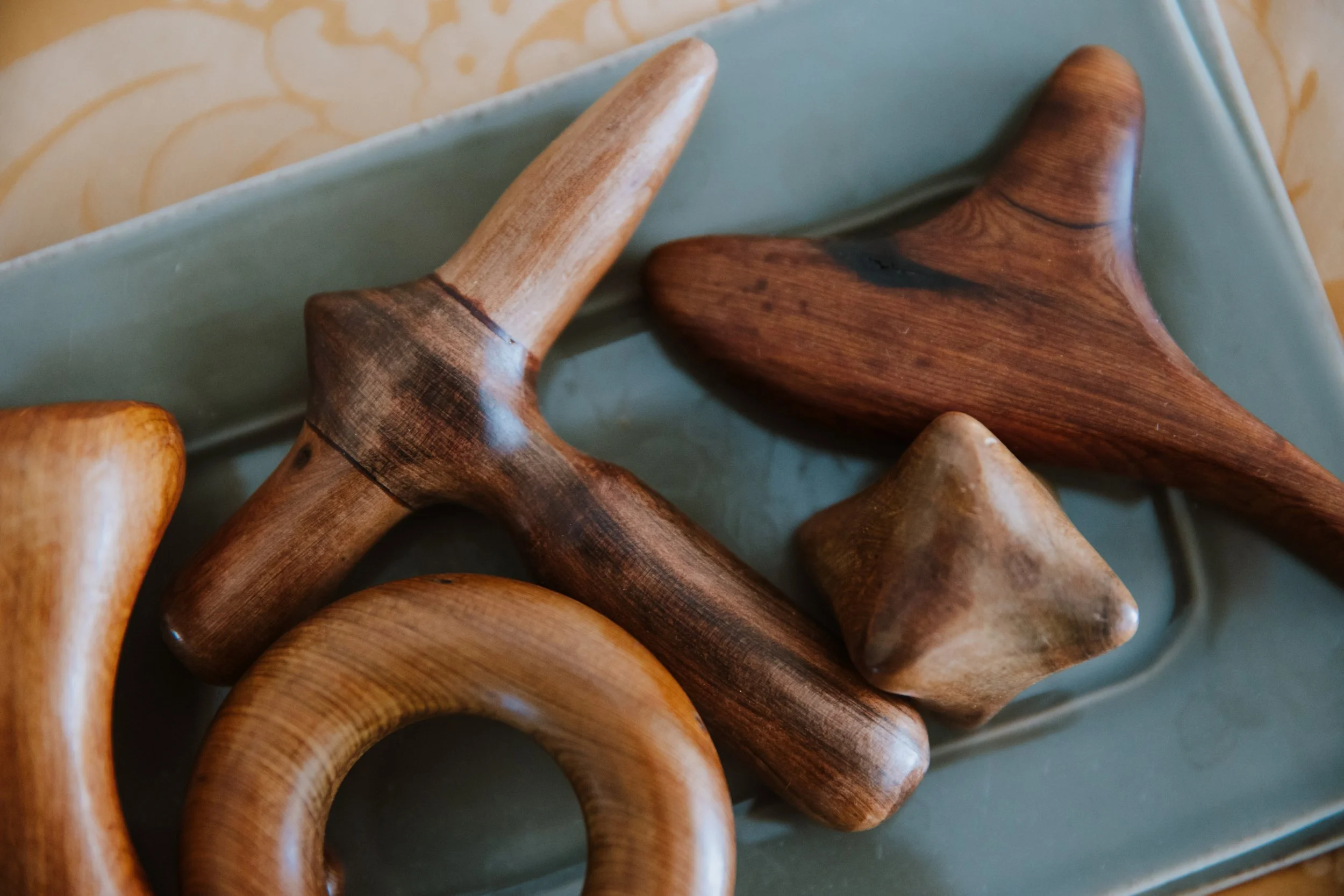 Vari pezzi di scultura in legno di diversi formi e colori su un piatto di ceramica