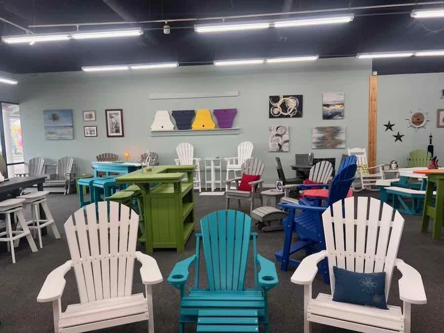 A showroom filled with colorful Adirondack chairs and tables, with artwork on the walls.
