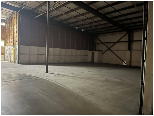 Empty warehouse with metal walls and a concrete floor.