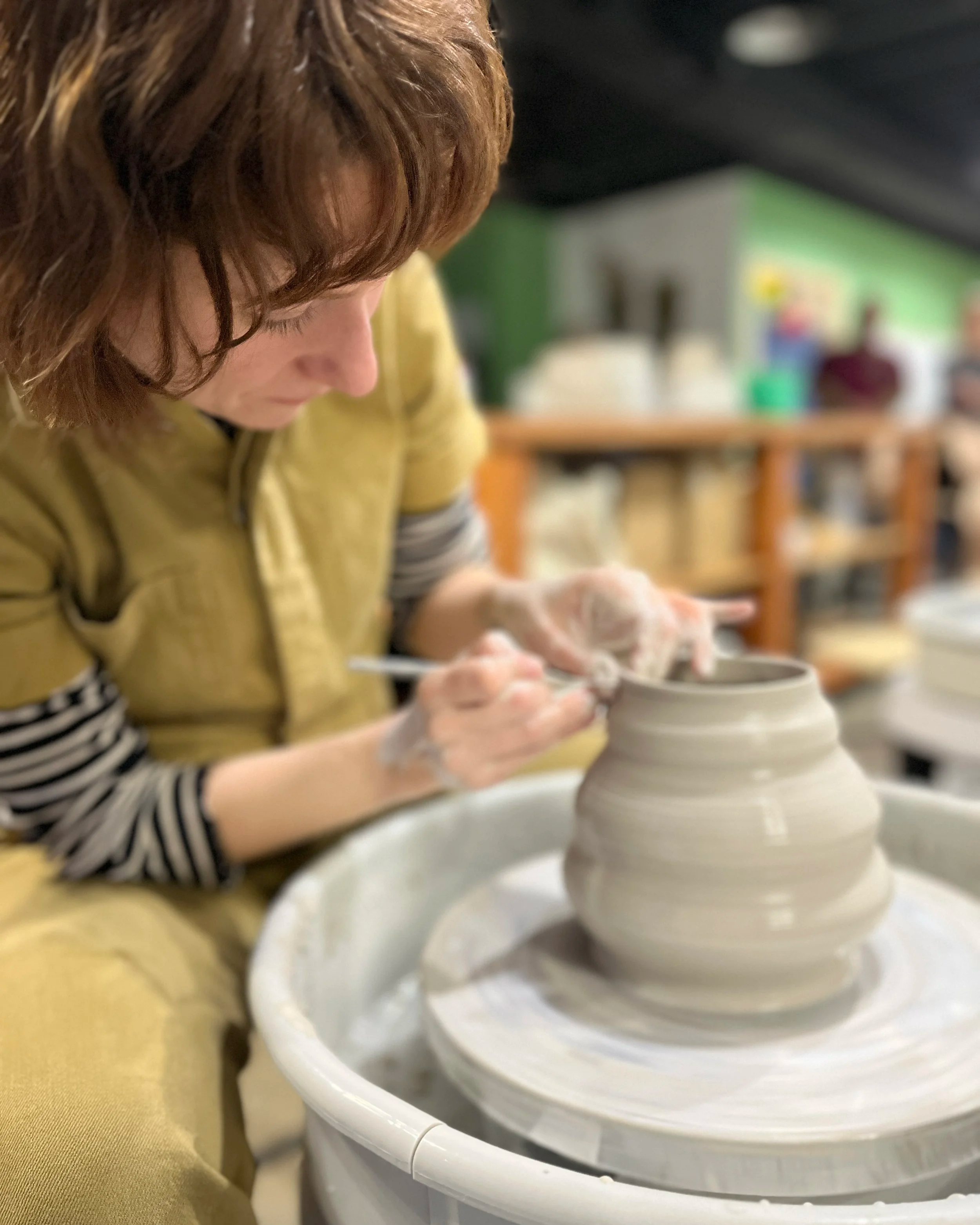 Someone working clay on a pottery wheel