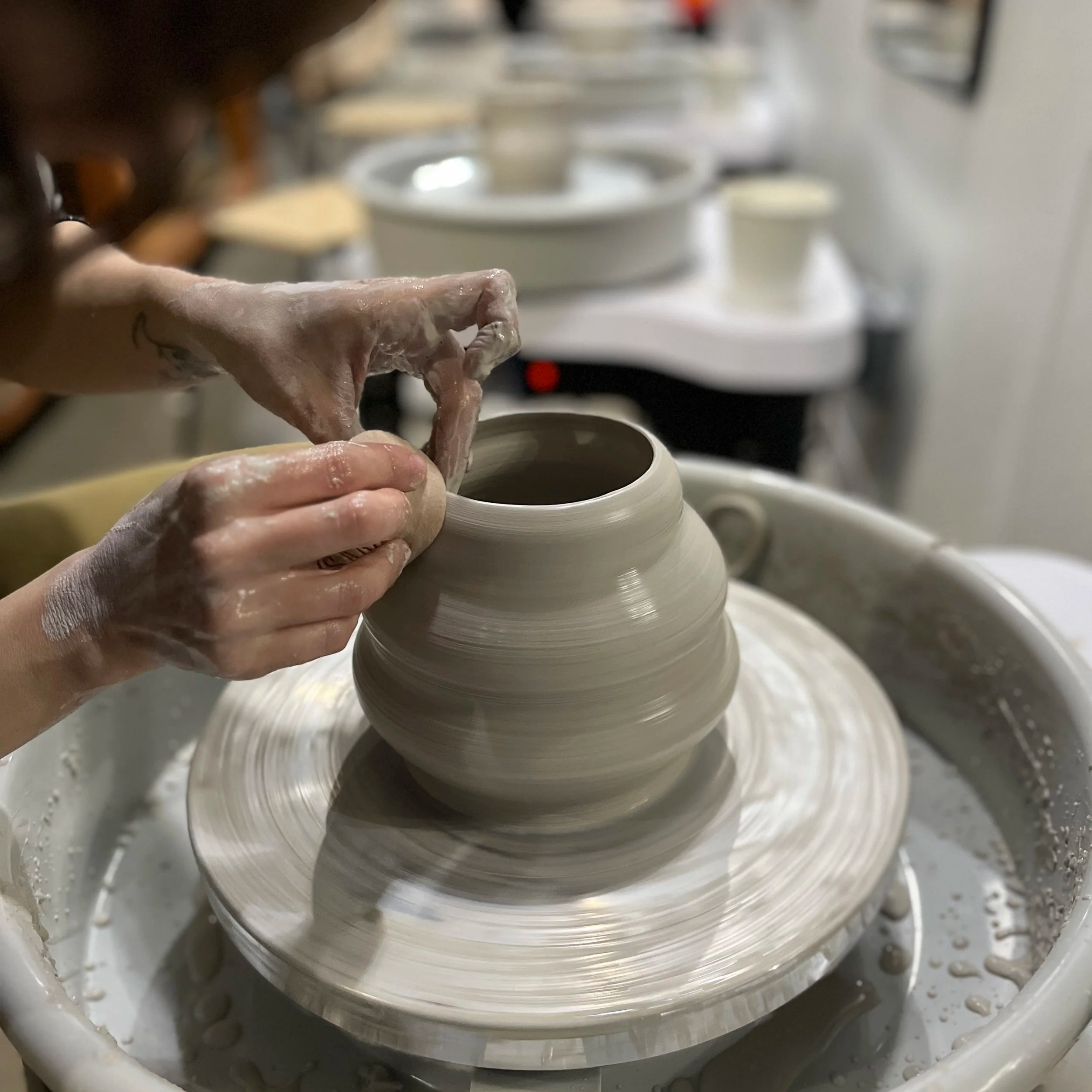 Someone working pottery on a wheel