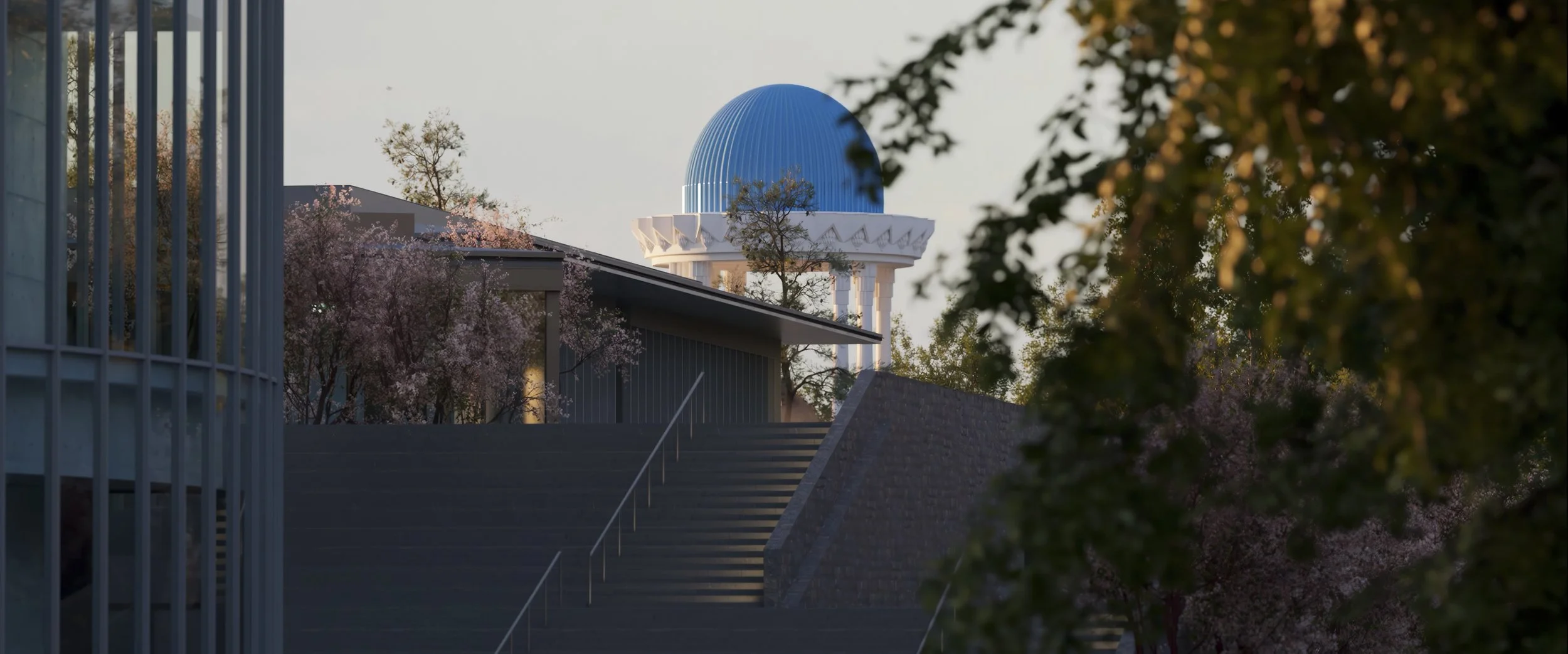 A blue observatory dome on top of a white structure, with flowering trees and a modern building in the foreground.