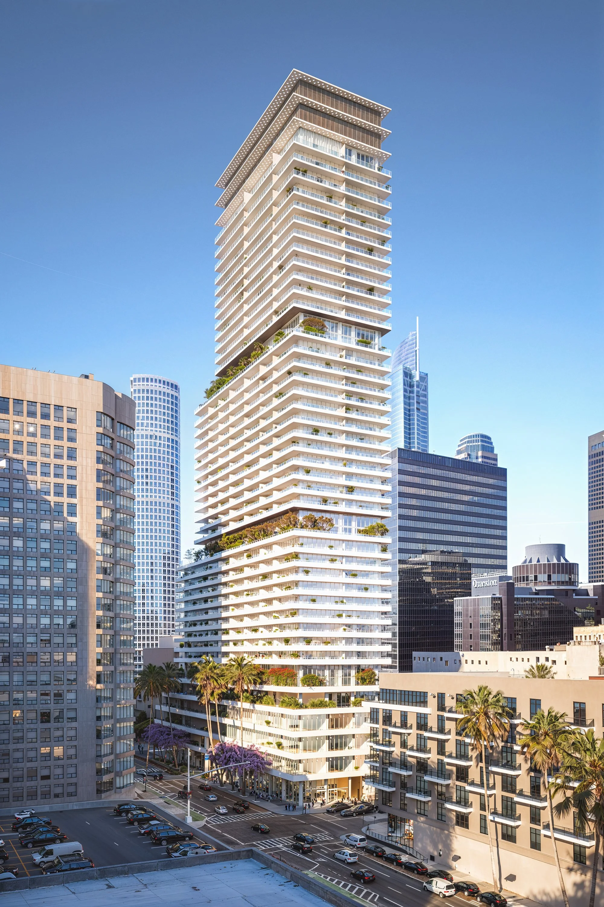 A tall, modern high-rise building with multiple terraces, plants, and trees, set against a clear blue sky. Surrounding the building are other skyscrapers and city buildings, with palm trees and a parking lot at the street level.