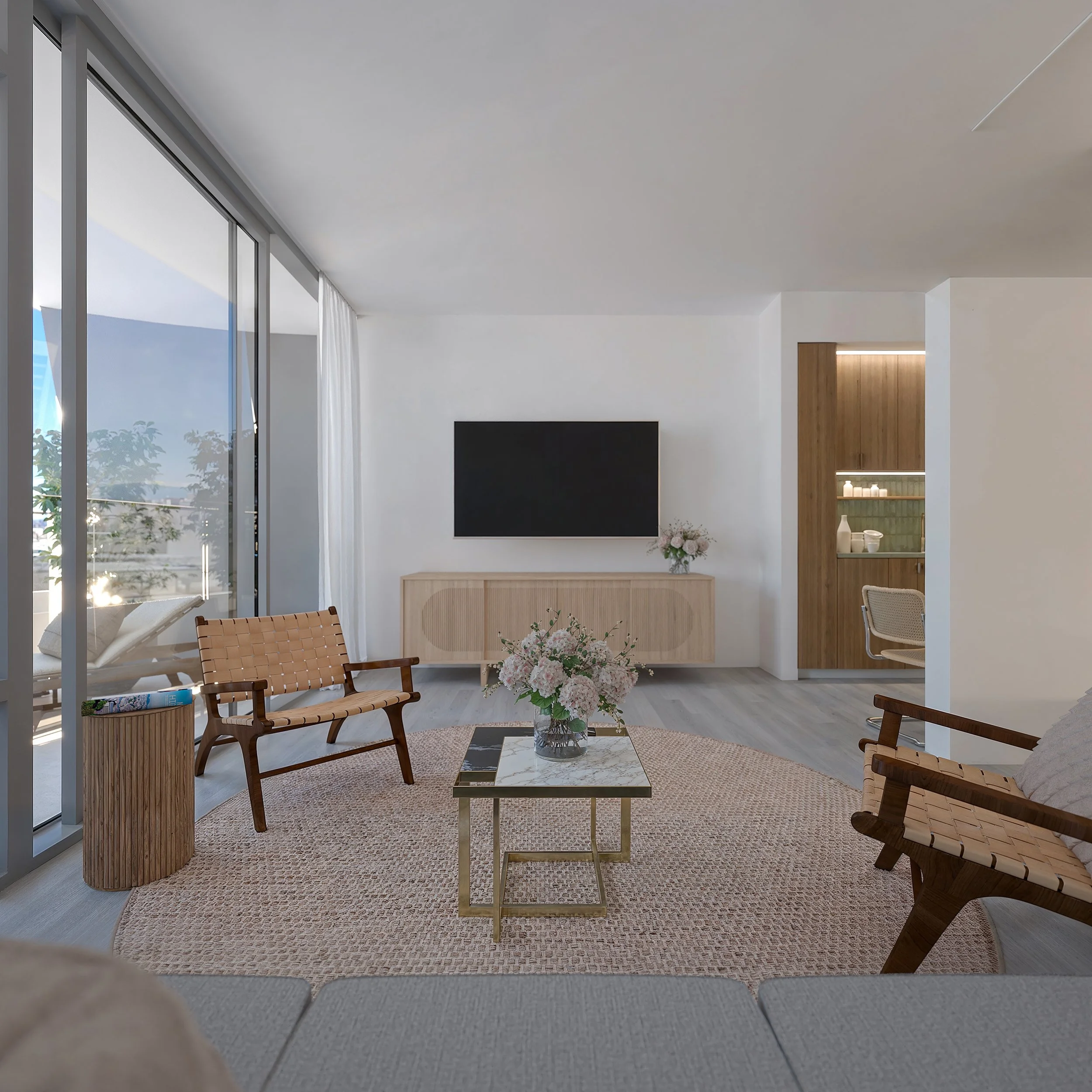 Modern living room with two wooden armchairs, a marble coffee table with a vase of pink flowers, a beige rug, a wall-mounted TV, and a sliding glass door leading to a balcony with outdoor furniture.