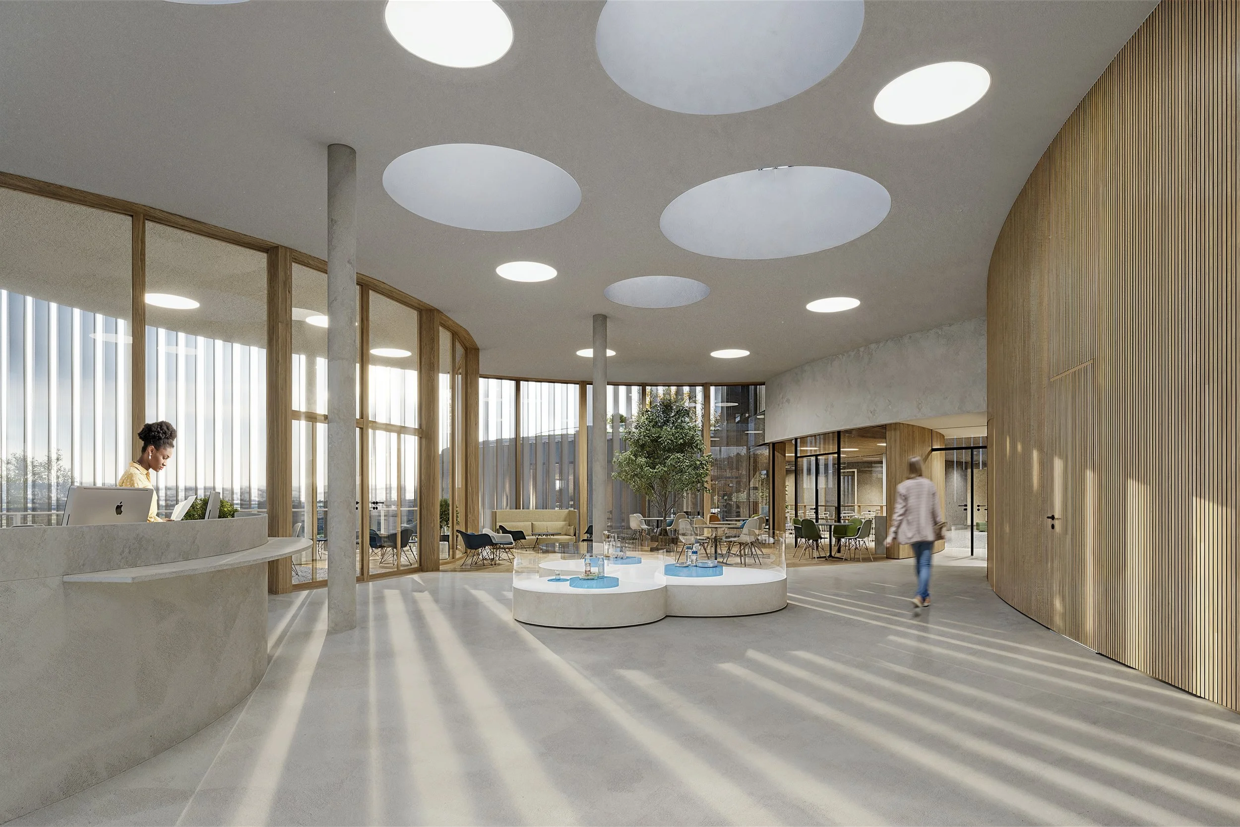 Modern interior lobby with large windows, circular ceiling lights, a reception desk with a woman working, a seating area with chairs and a tree in the center, and a person walking.