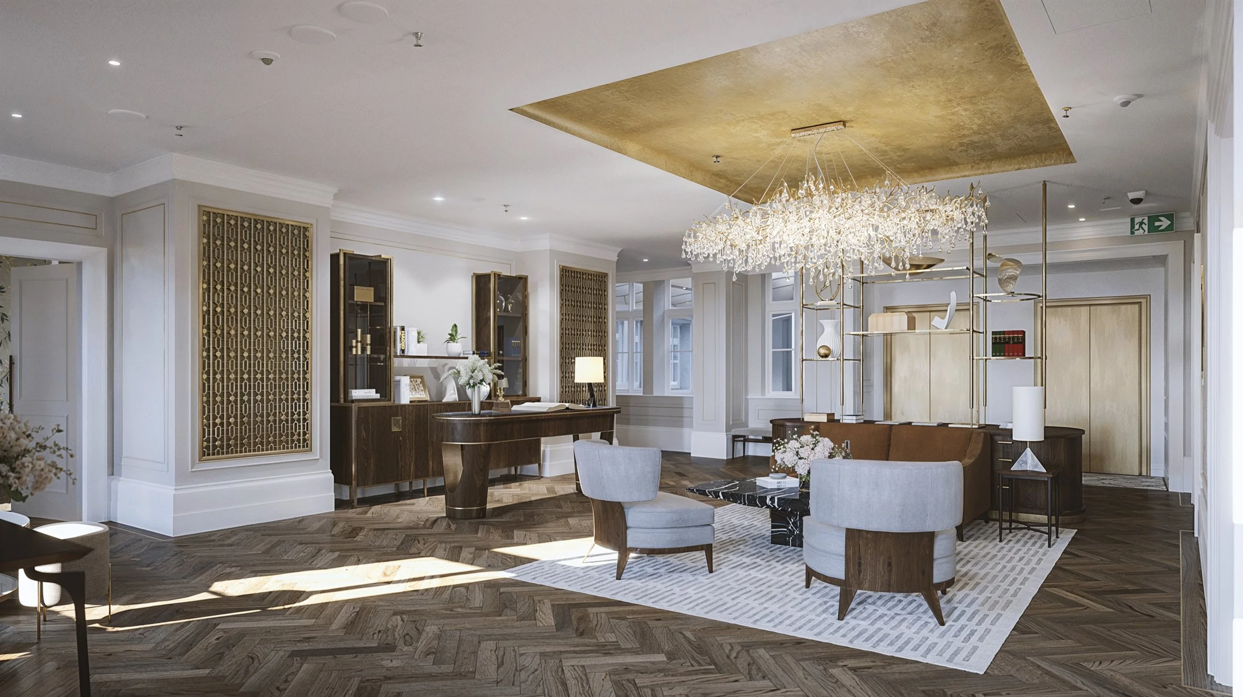 A luxurious hotel lobby with a modern and elegant design. It features a large, ornate chandelier hanging from a gold-accented ceiling panel. The furniture includes light gray armchairs and a dark marble coffee table on a white patterned rug. There is