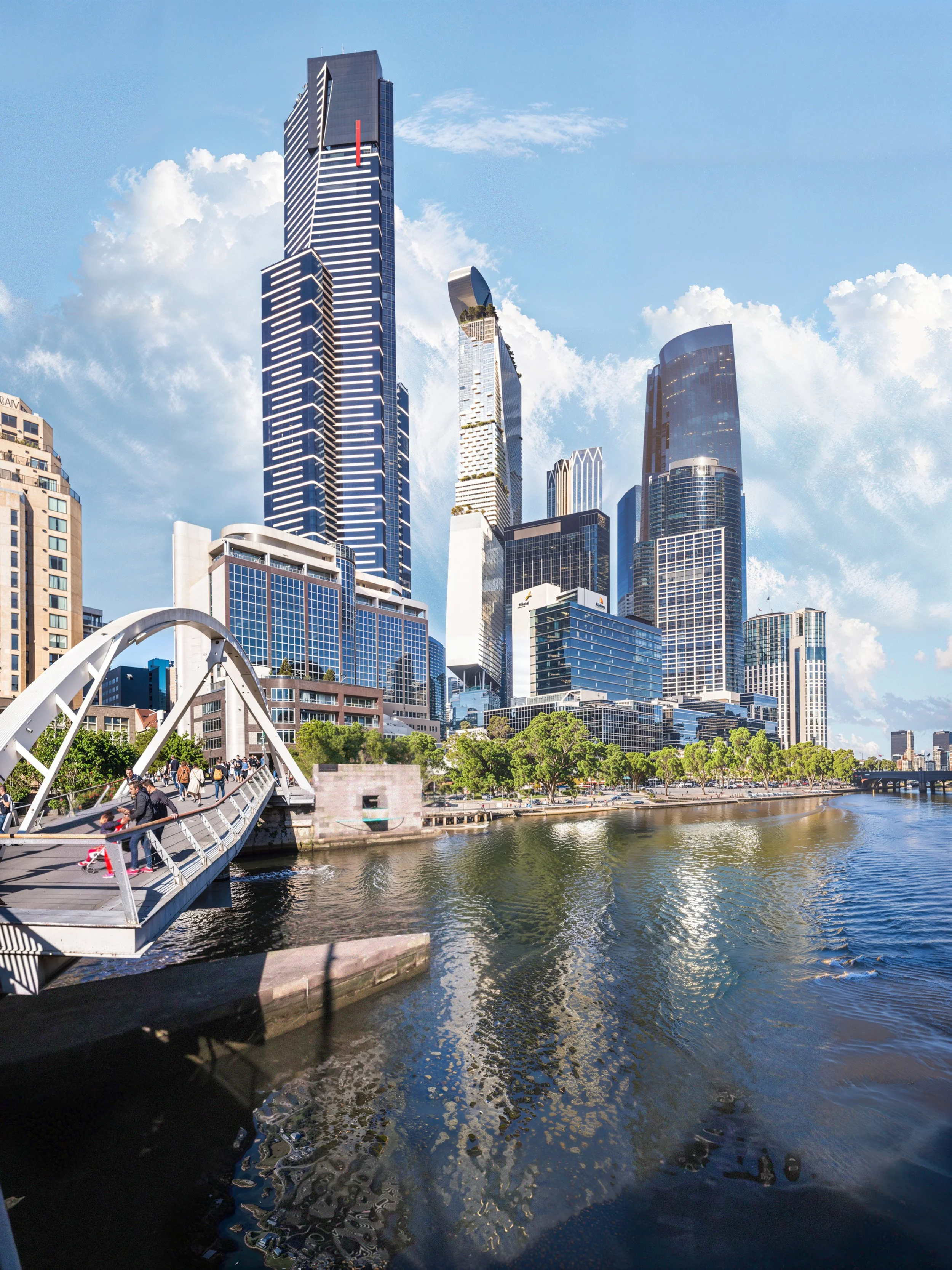 Skyscrapers in a city skyline with reflections on a river and a white pedestrian bridge in the foreground.