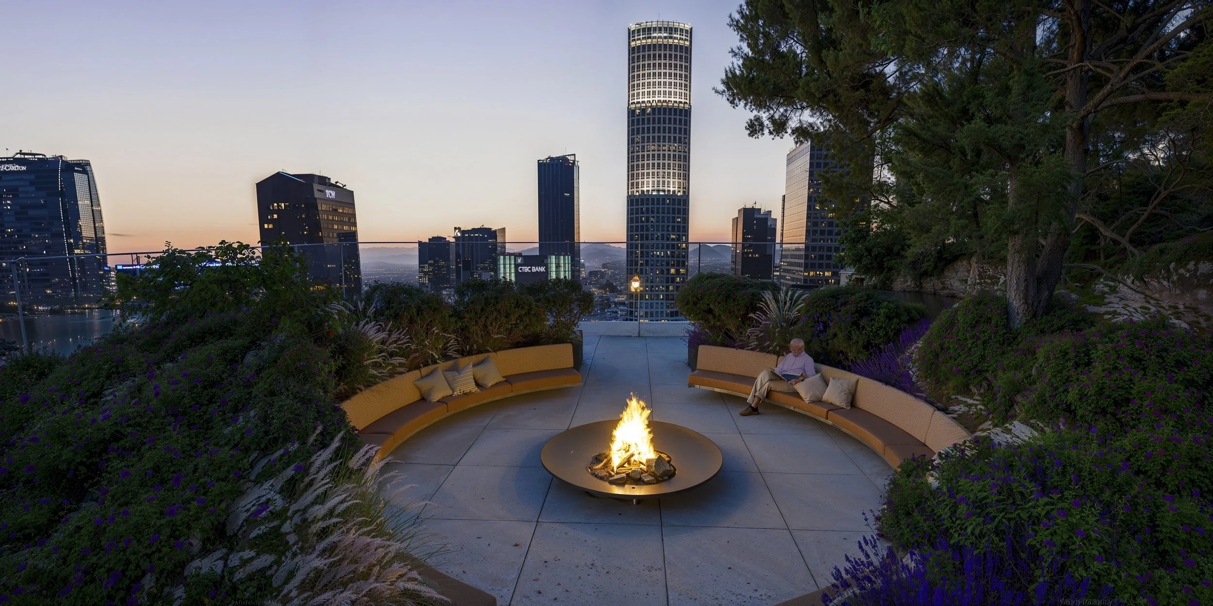 City skyline at twilight with tall buildings and a fire pit in the foreground surrounded by curved benches and greenery, with a person reading a book on the right bench.