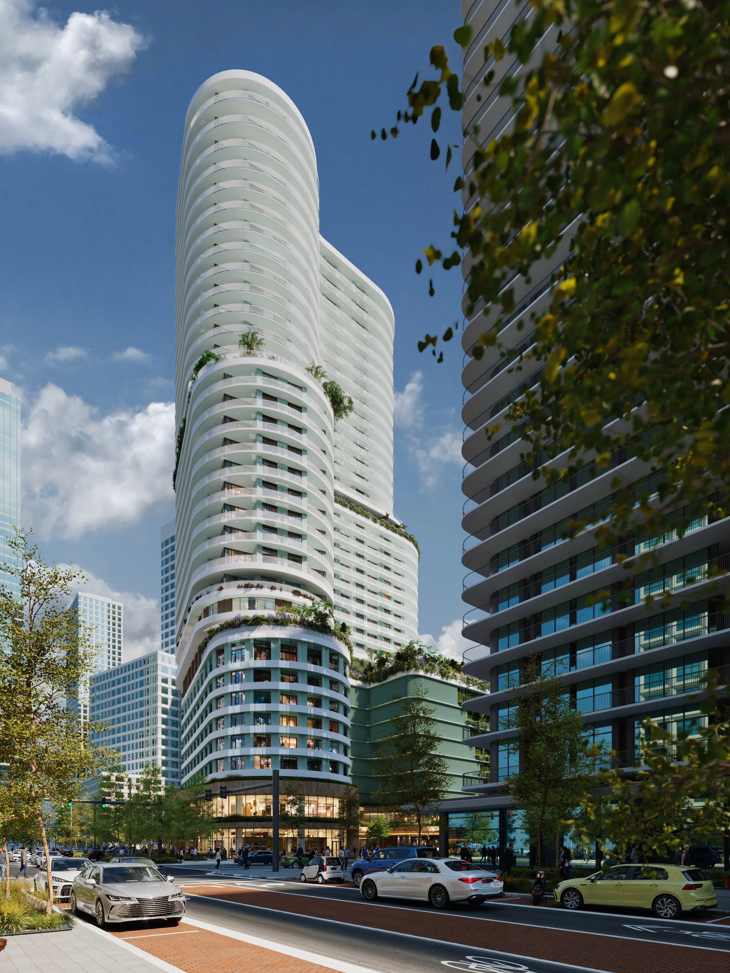 A modern, white high-rise building with curved balconies and greenery on some terraces, surrounded by other tall buildings and trees, with cars and pedestrians on the street in the foreground.