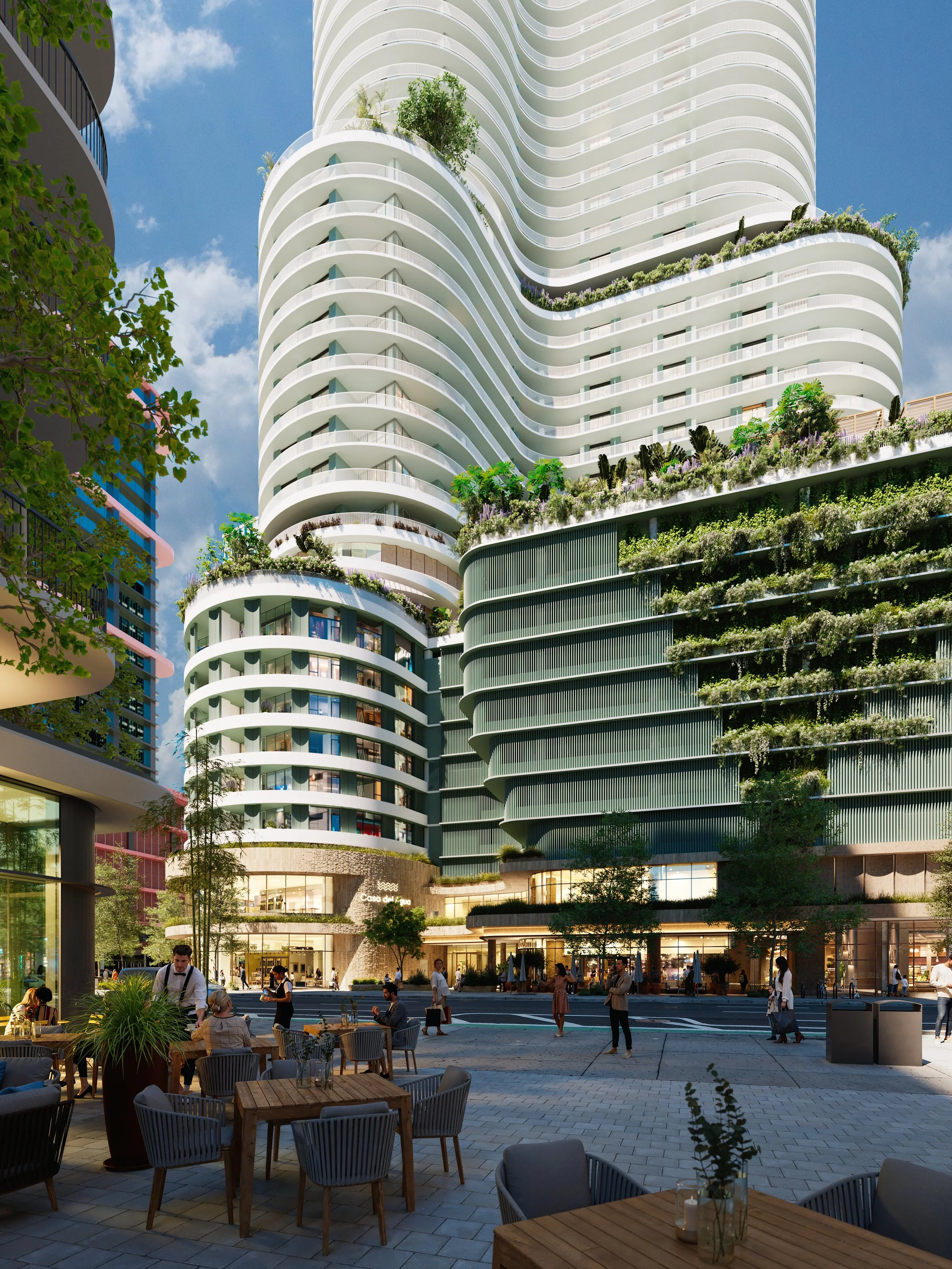 Modern high-rise building with curved white and green tiers, featuring rooftop gardens and outdoor terraces, situated in an urban area with a patio at the base where people are dining and walking.