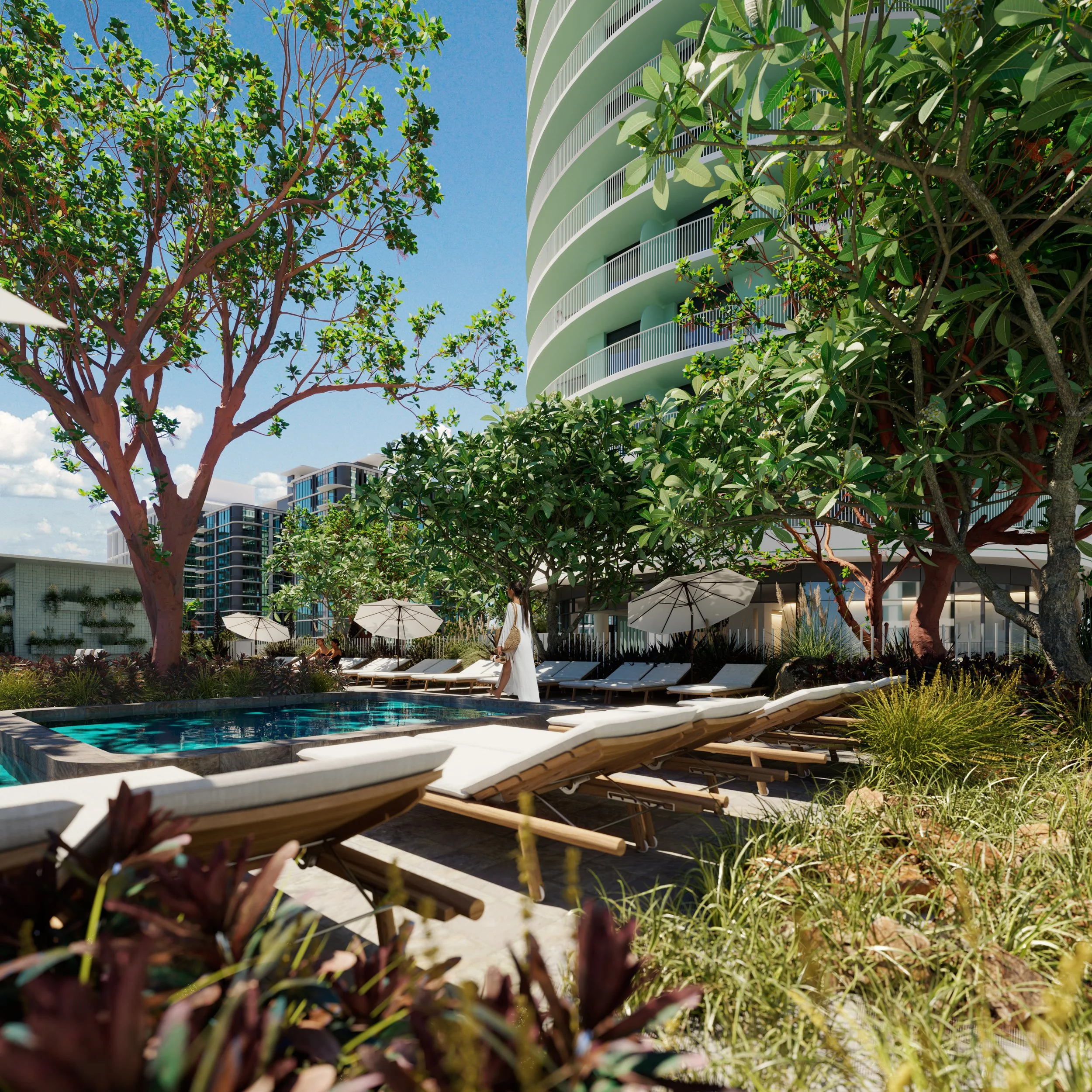 A rooftop pool area with lounge chairs, umbrellas, and lush green trees, with a modern high-rise building in the background under a clear blue sky.