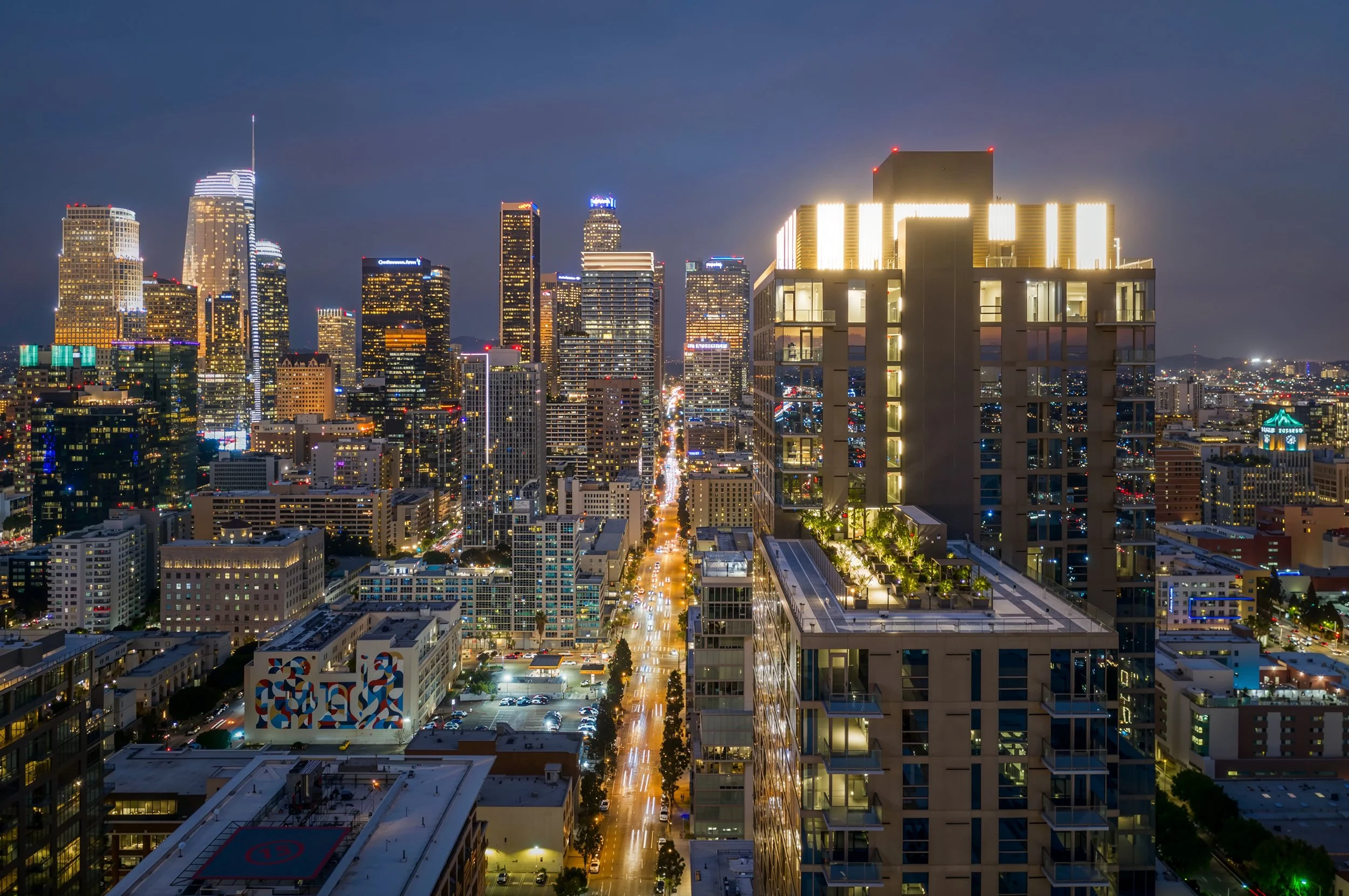 Nighttime cityscape of downtown Los Angeles with illuminated skyscrapers and streets.