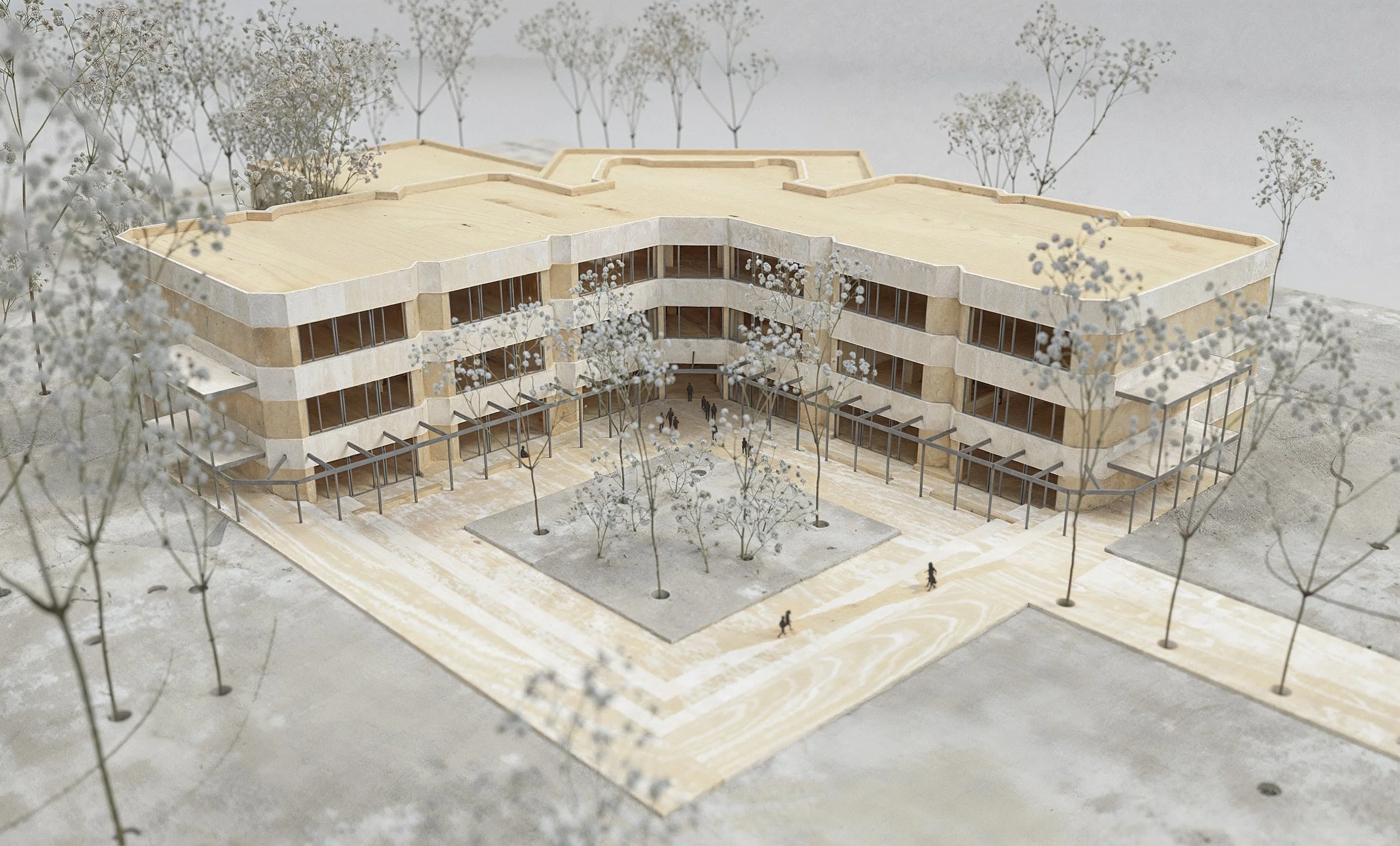Architectural model of a modern multi-story building with landscaped courtyard and surrounding trees