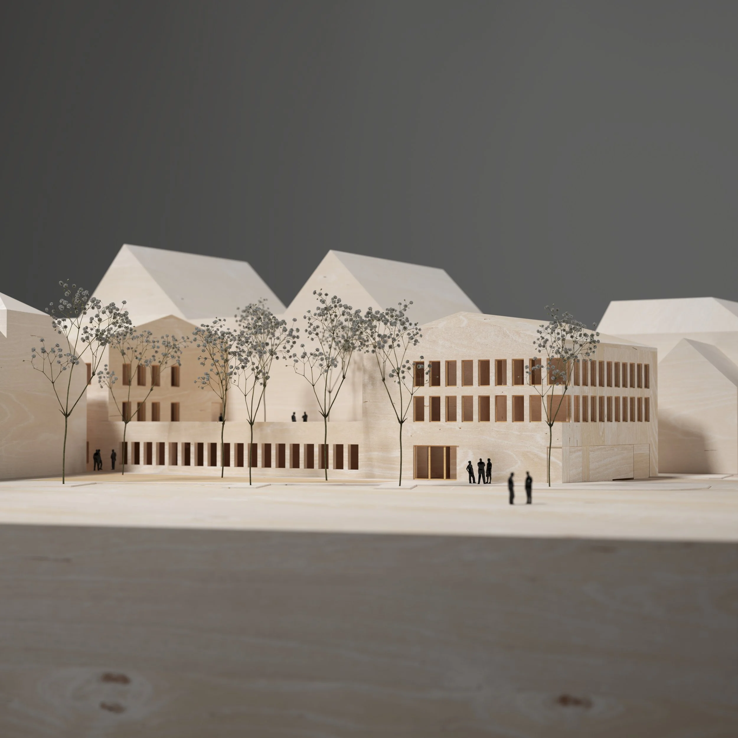 Architectural model of a modern building complex with multiple stories, surrounded by trees, with several miniature figures of people.