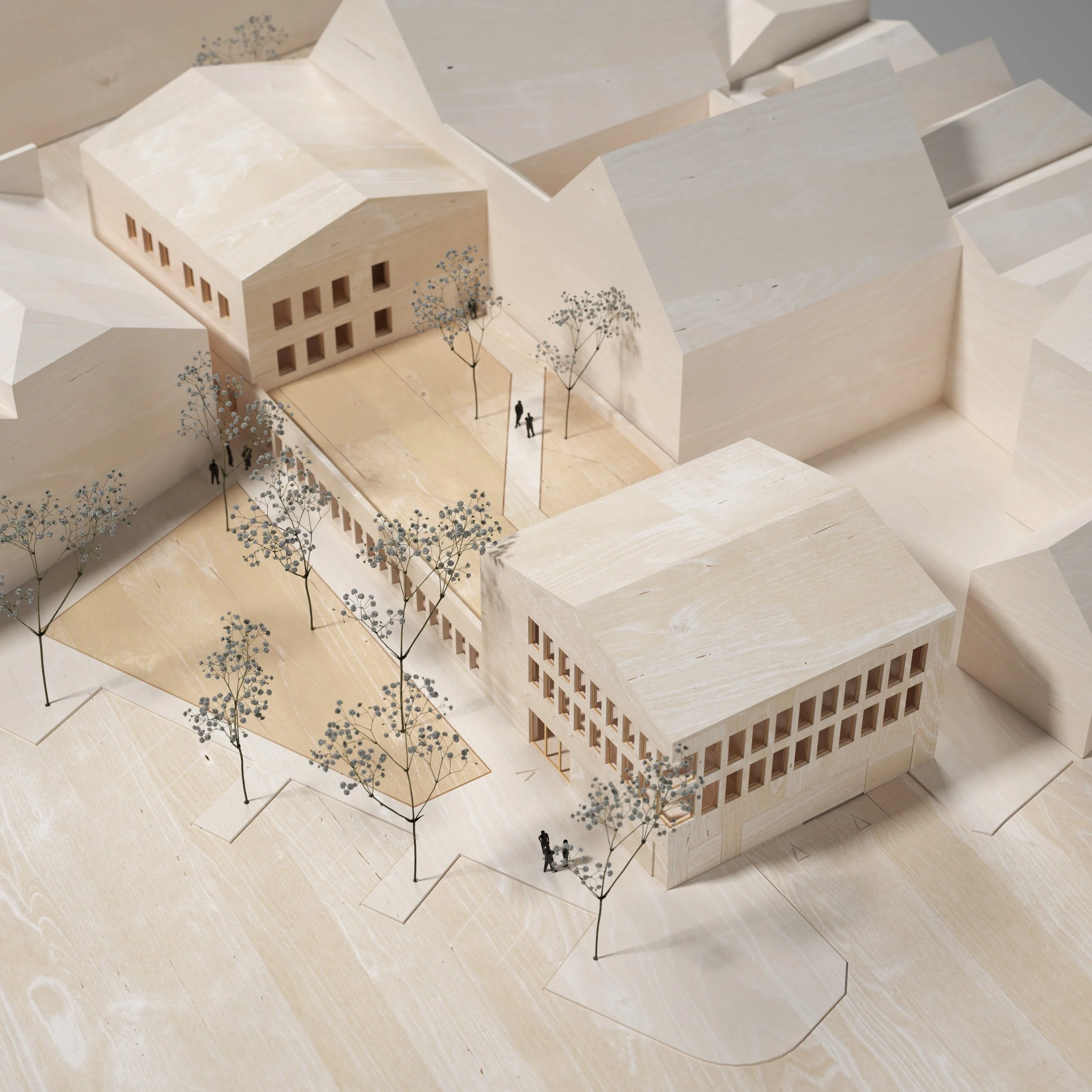 Architectural scale model of a building complex with trees and small human figures for scale.