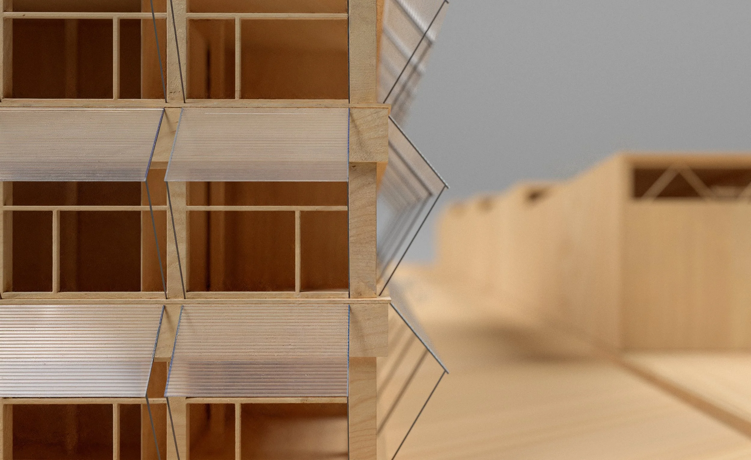 Close-up of a wooden architectural model with multiple levels and open spaces, featuring thin metal wires.