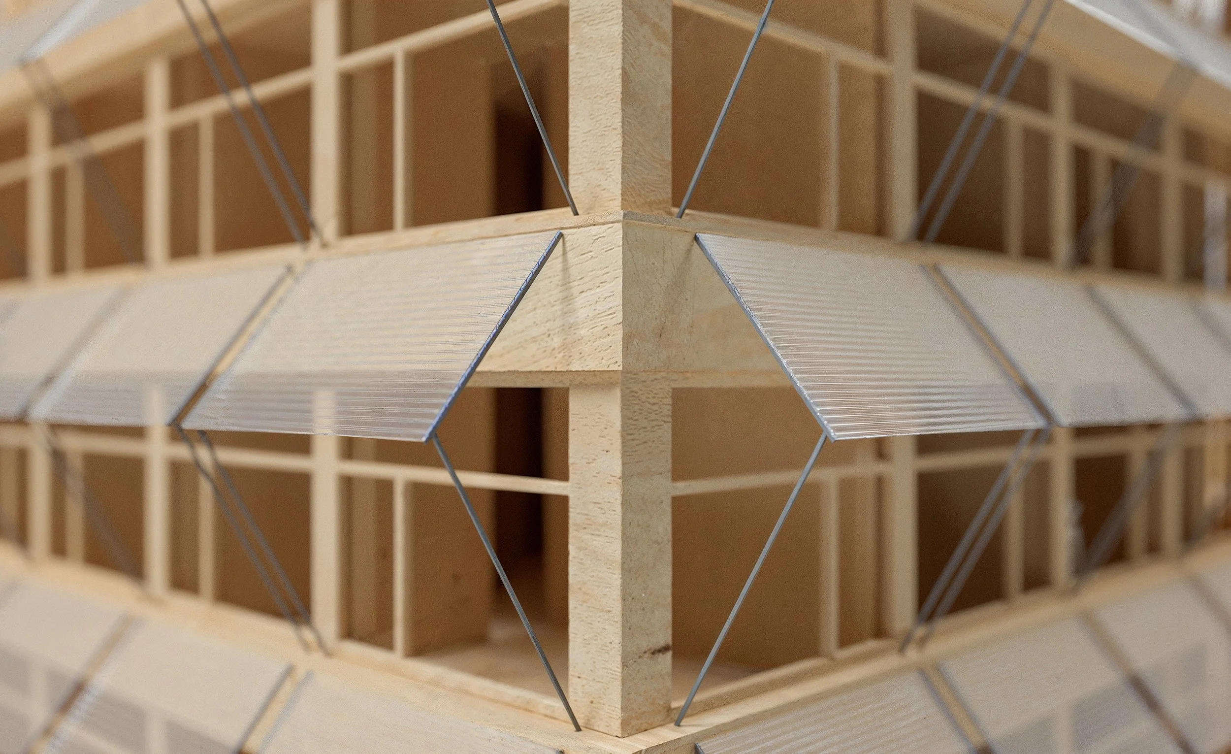 Close-up view of a wooden architectural model with grid framework and metal rods, showing detailed construction elements.