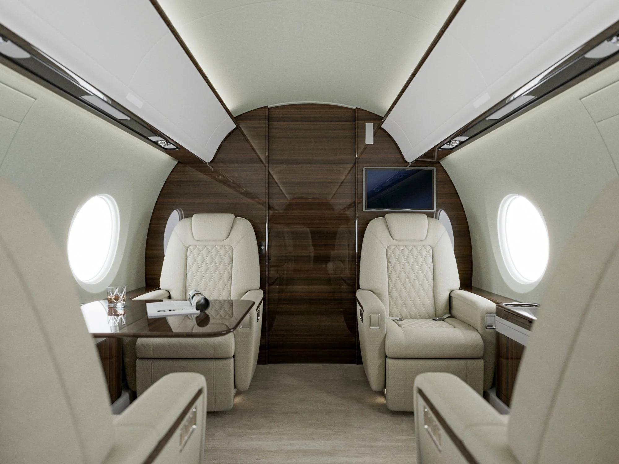 Interior of a private jet with two beige leather seats, a small glass, a microphone, a TV screen, and large oval windows.