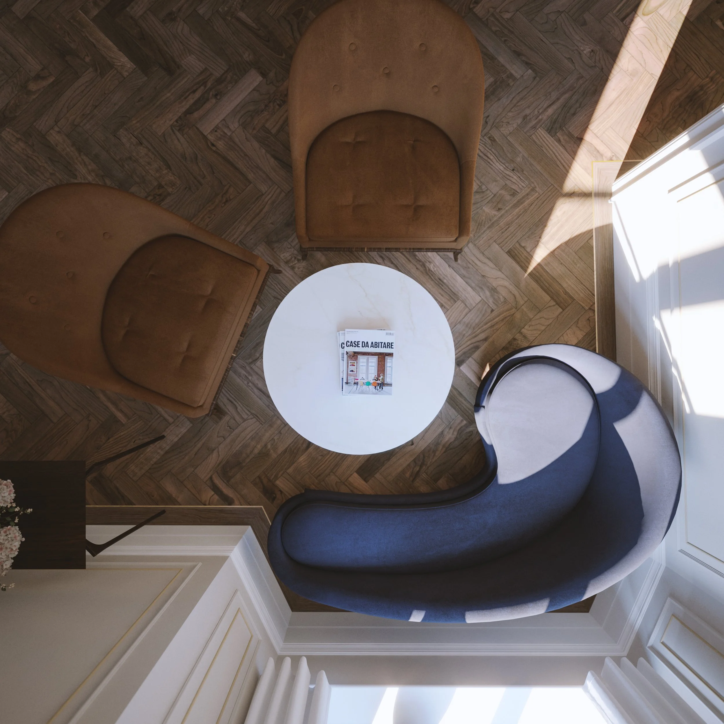 Overhead view of a sitting area with two brown armchairs, a white round coffee table with magazines, and a curved gray sofa near a large window with sunlight and shadows.