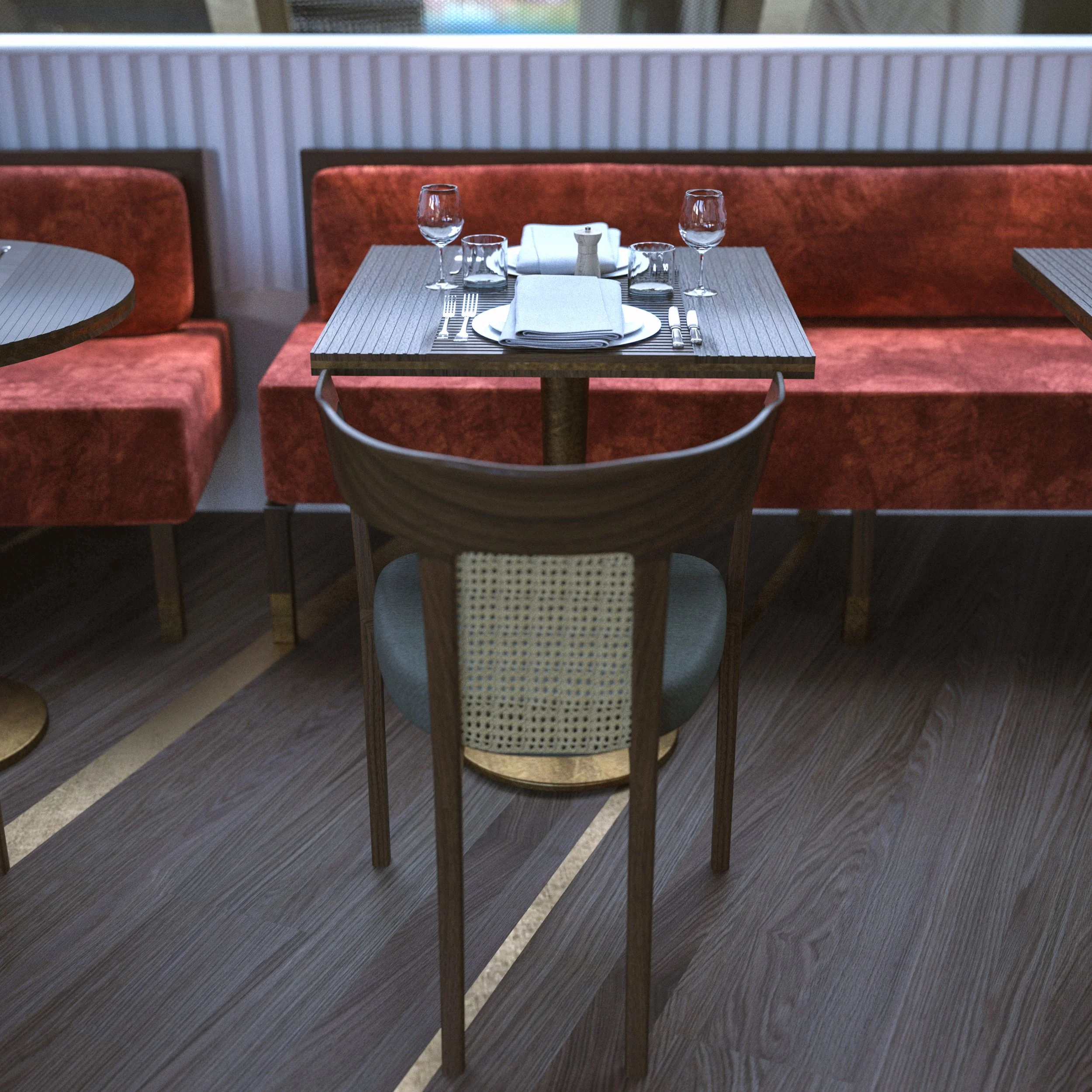 Empty restaurant table set with glasses, silverware, and napkins, with seating and a window in the background.