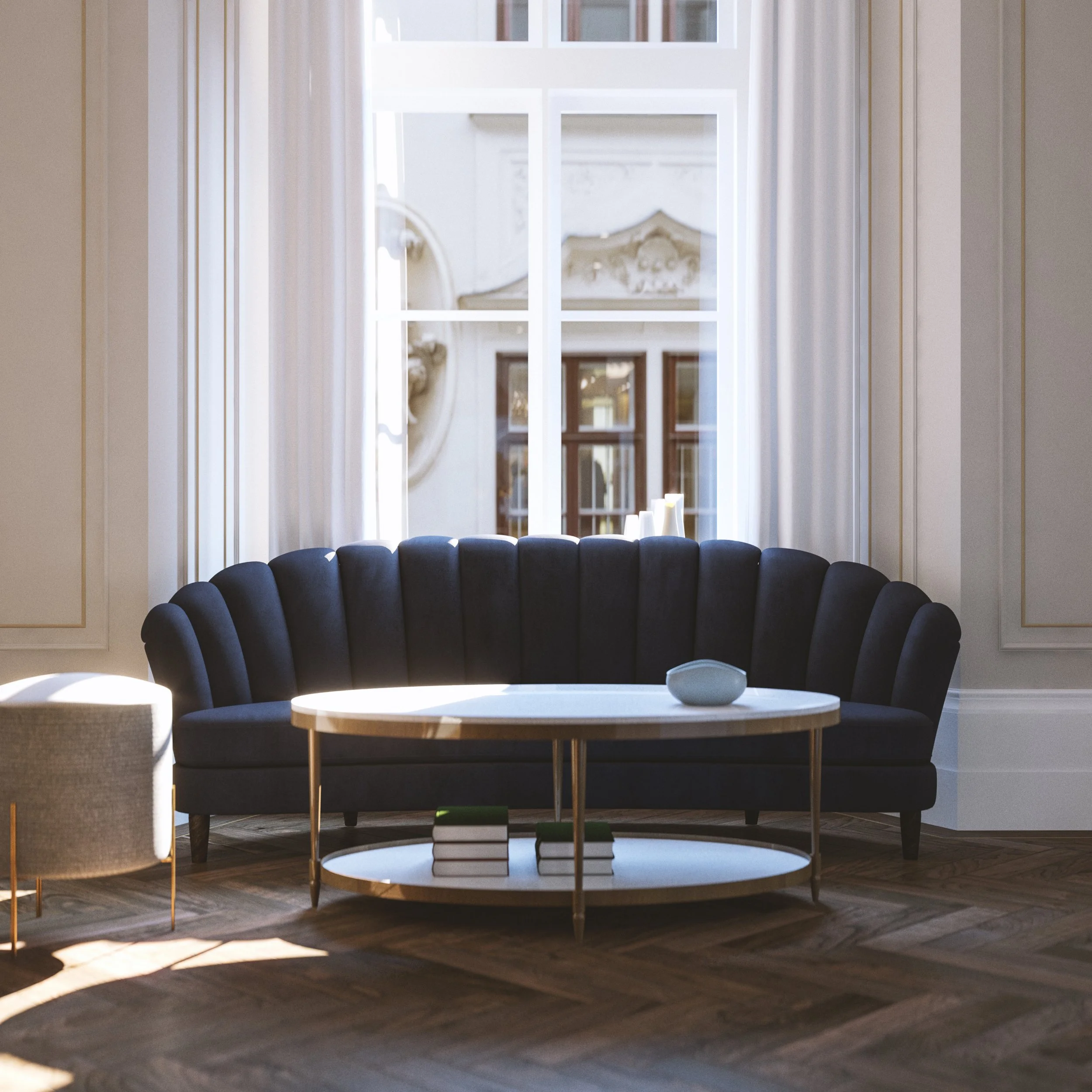 A living room with a large window, a navy blue curved sofa, a white oval coffee table with books underneath, and a decorative object on top. Sunlight streams into the room, illuminating the space.