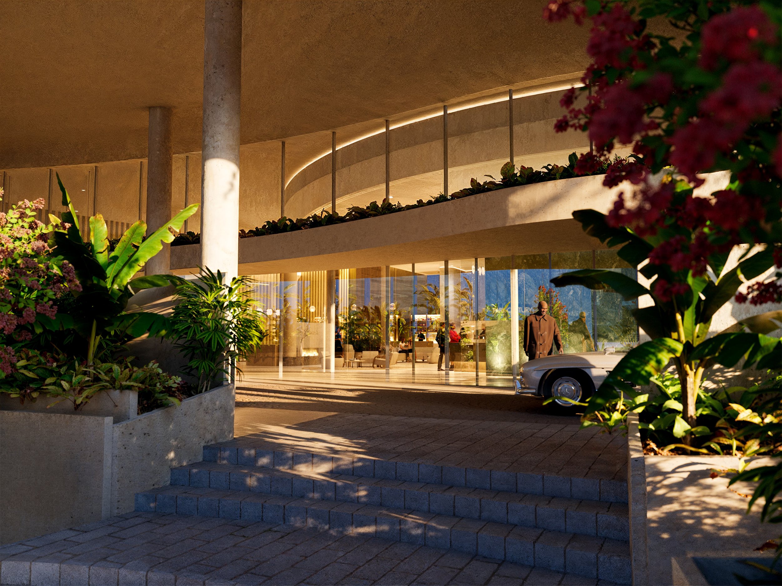 Modern building with glass doors, concrete pillars, and two levels, surrounded by lush green plants and pink flowering bushes. A vintage car is parked outside, and a person in a brown coat is standing near the entrance. The interior is visible throug