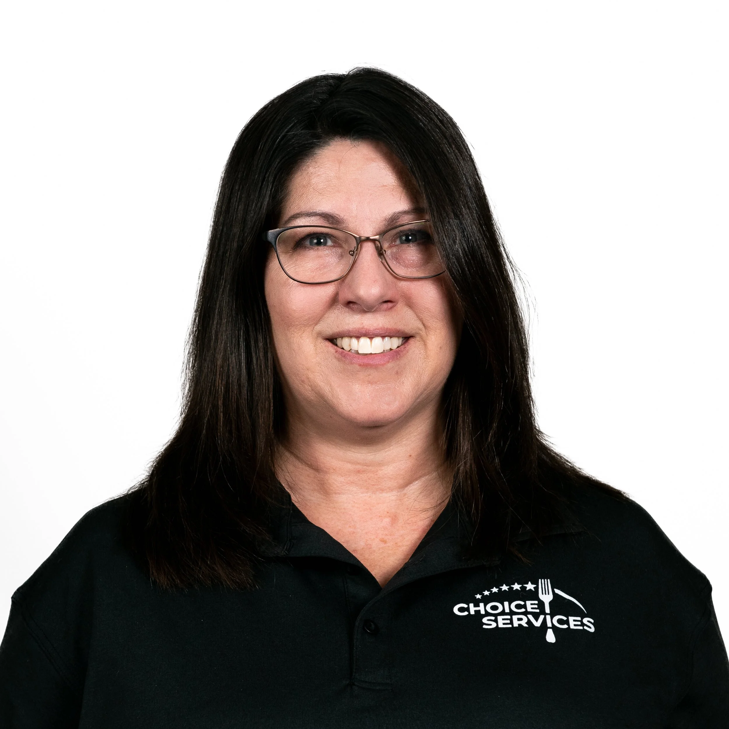 Portrait of a woman with shoulder-length dark hair, glasses, and a black polo shirt with 'Choice Services' logo, smiling at the camera.