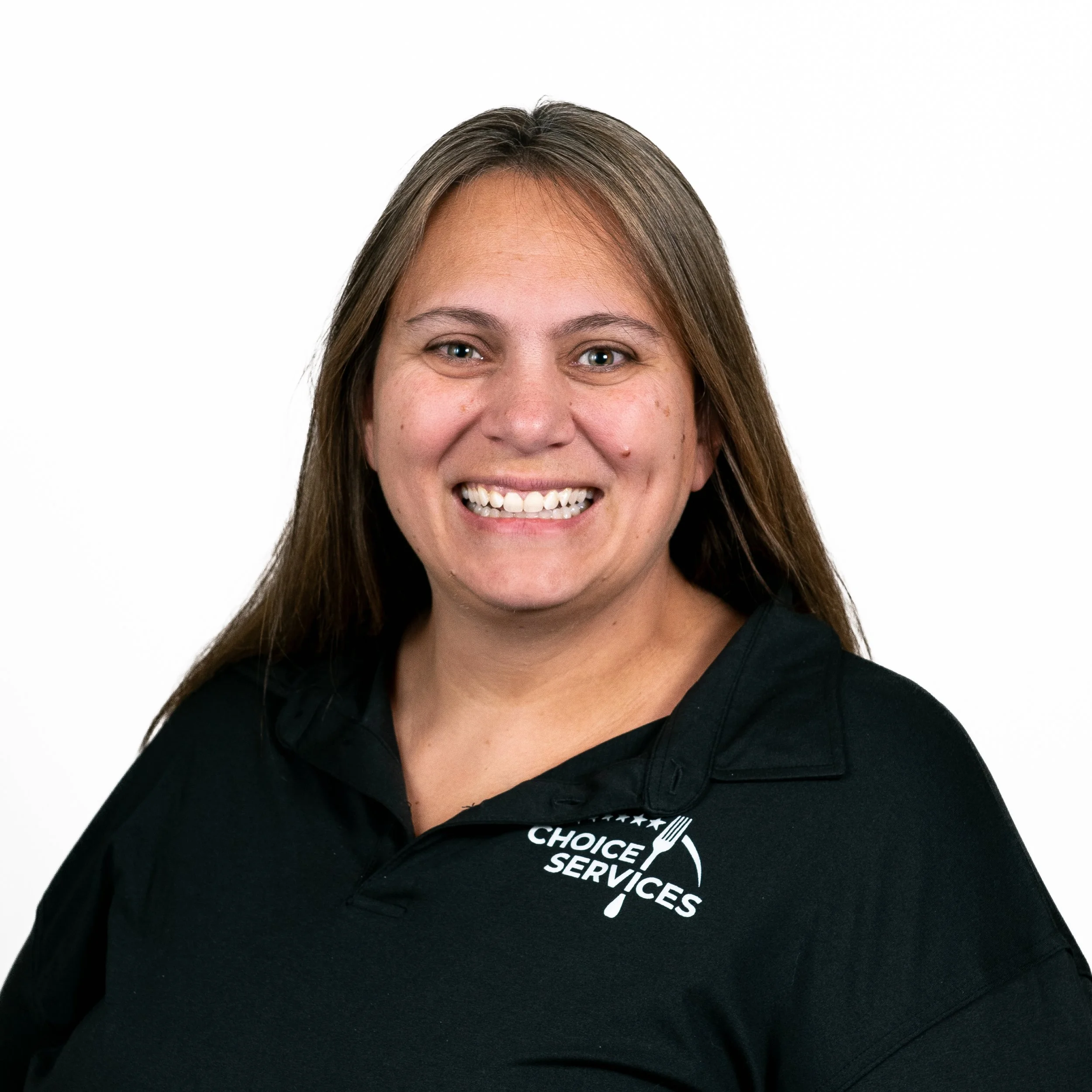 Portrait of a woman with long brown hair, smiling, wearing a black polo shirt with a 'Choice Services' logo.