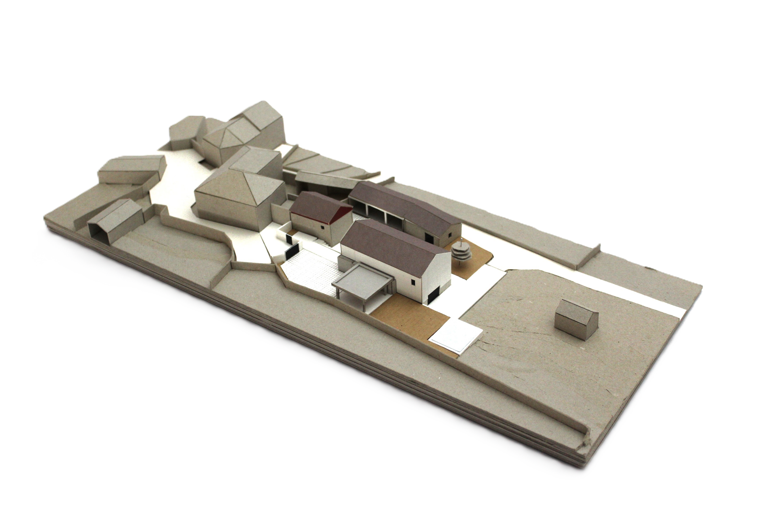 Maquete de um projeto de arquitetura residencial com várias casinhas e espaços ao ar livre em uma base de papelão.