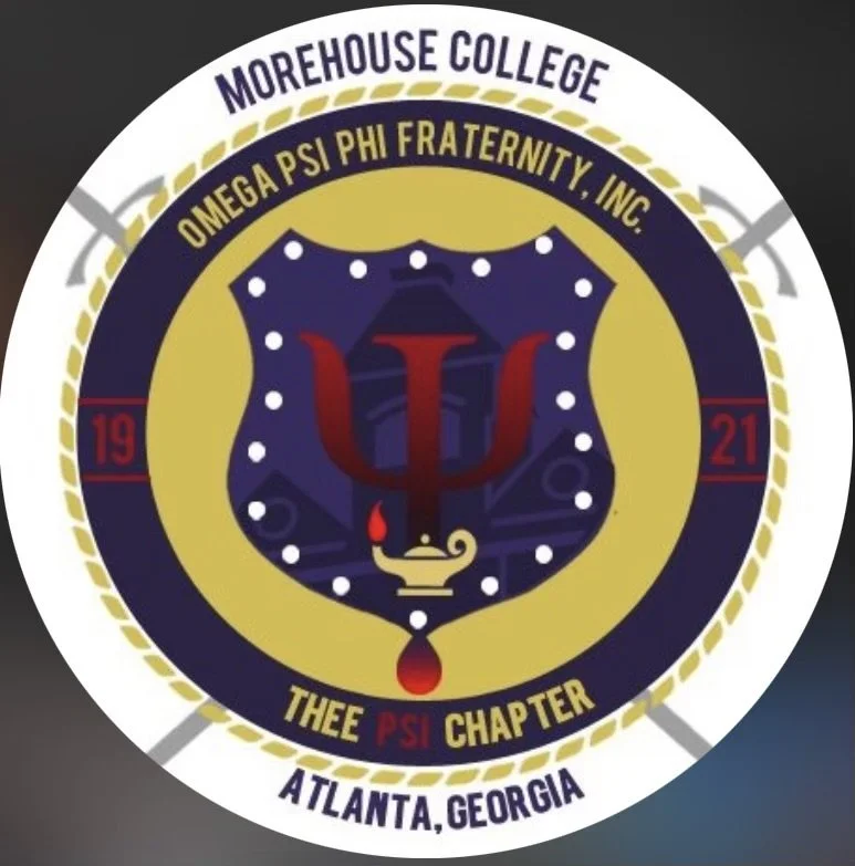 A circular emblem representing Morehouse College's Omega Psi Phi Fraternity, Inc. The emblem features the Greek letter Psi, a lamp, and a blood drop in the center. The outer ring includes the fraternity's name, chapter information, and location in Atlanta, Georgia.
