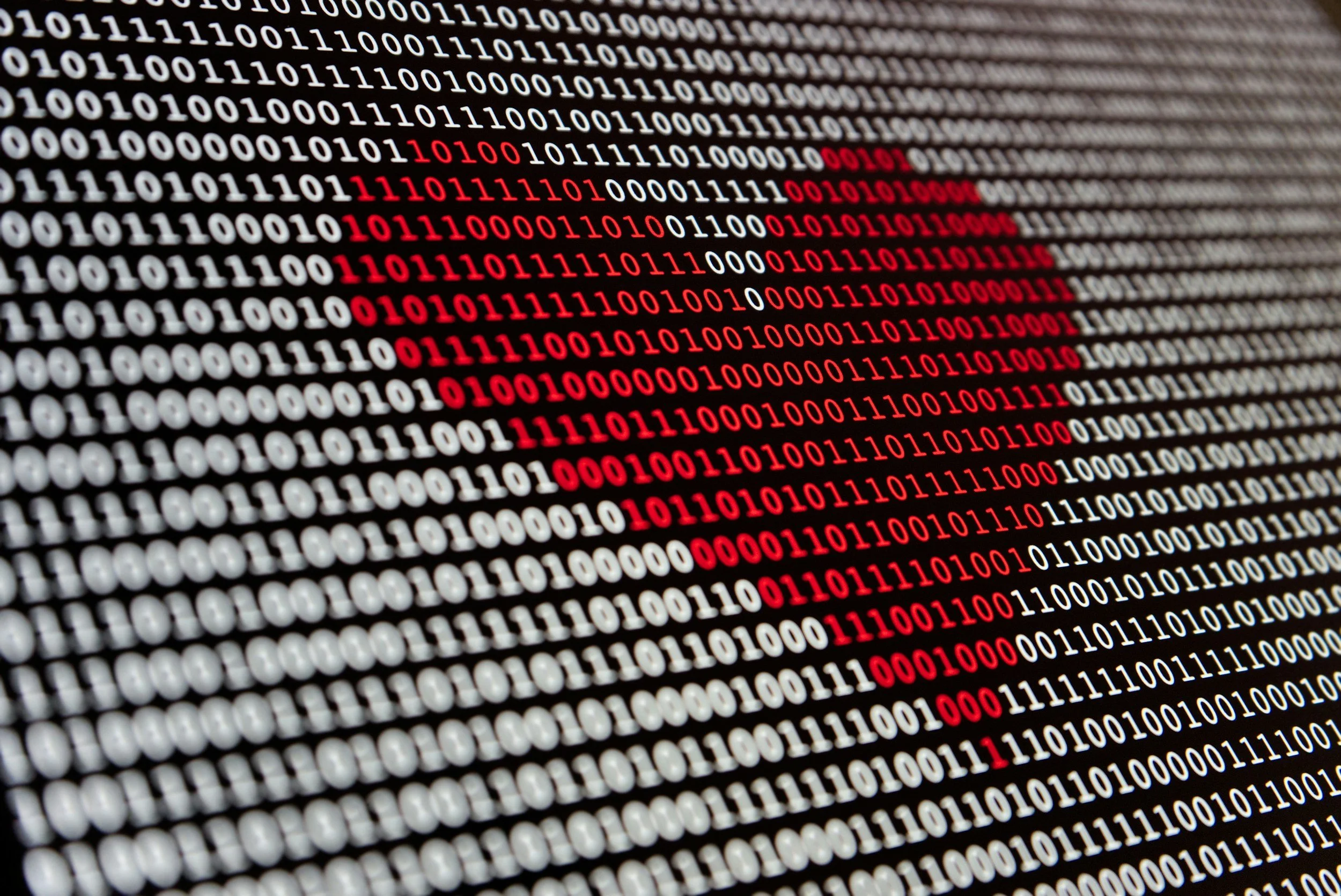 Een computerscherm met rode en witte bits in een binaire code, waarbij enkele rode bits vormen een diagonaal patroon.