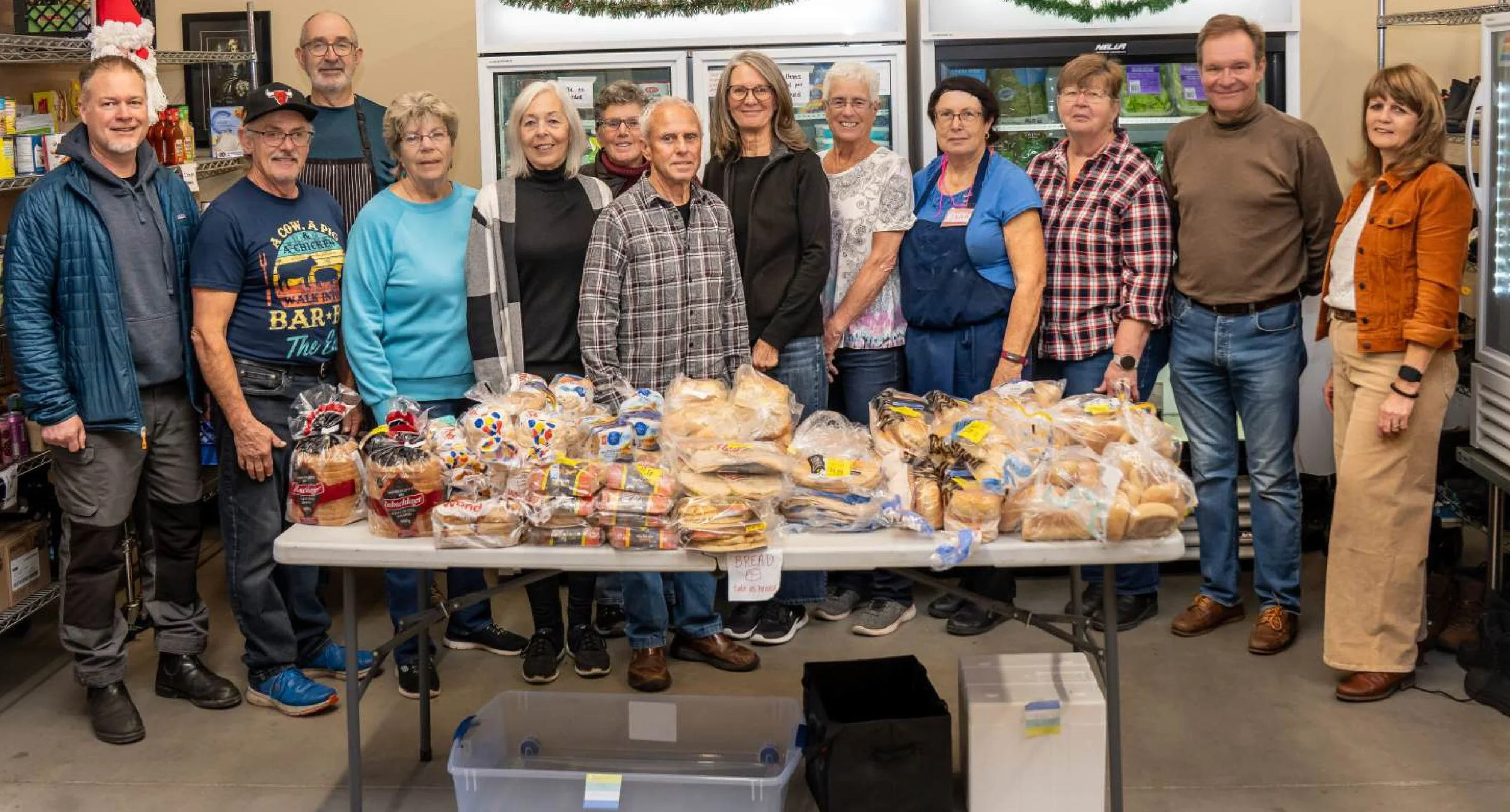 Group of people standing behind a table of bread at the food bank