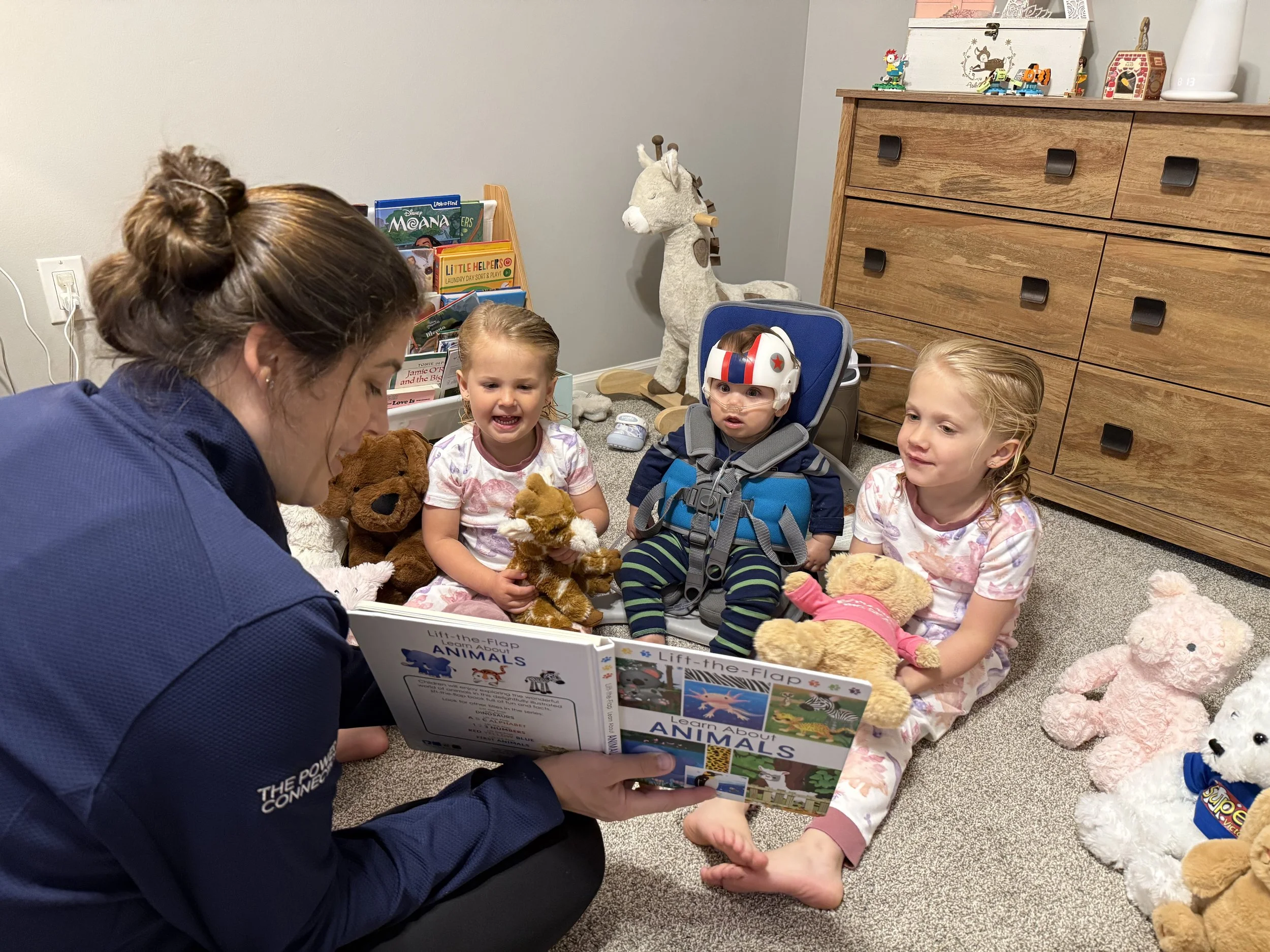 Liam using a device that helps him sit up so he can participate in story time with his family.