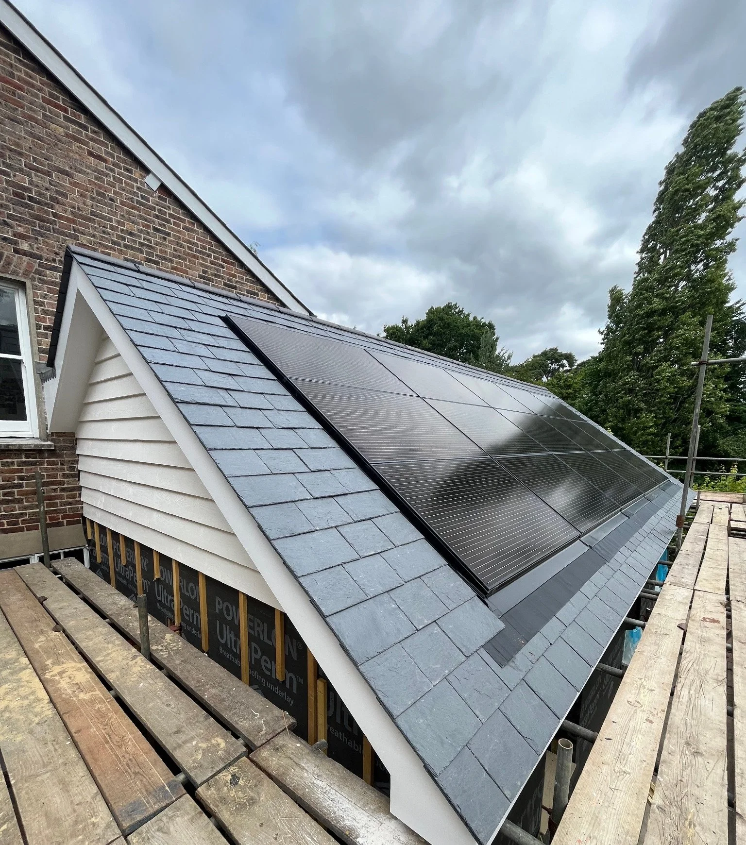 Roof detail of a Lindfield property featuring new slate tiles and integrated solar panels.