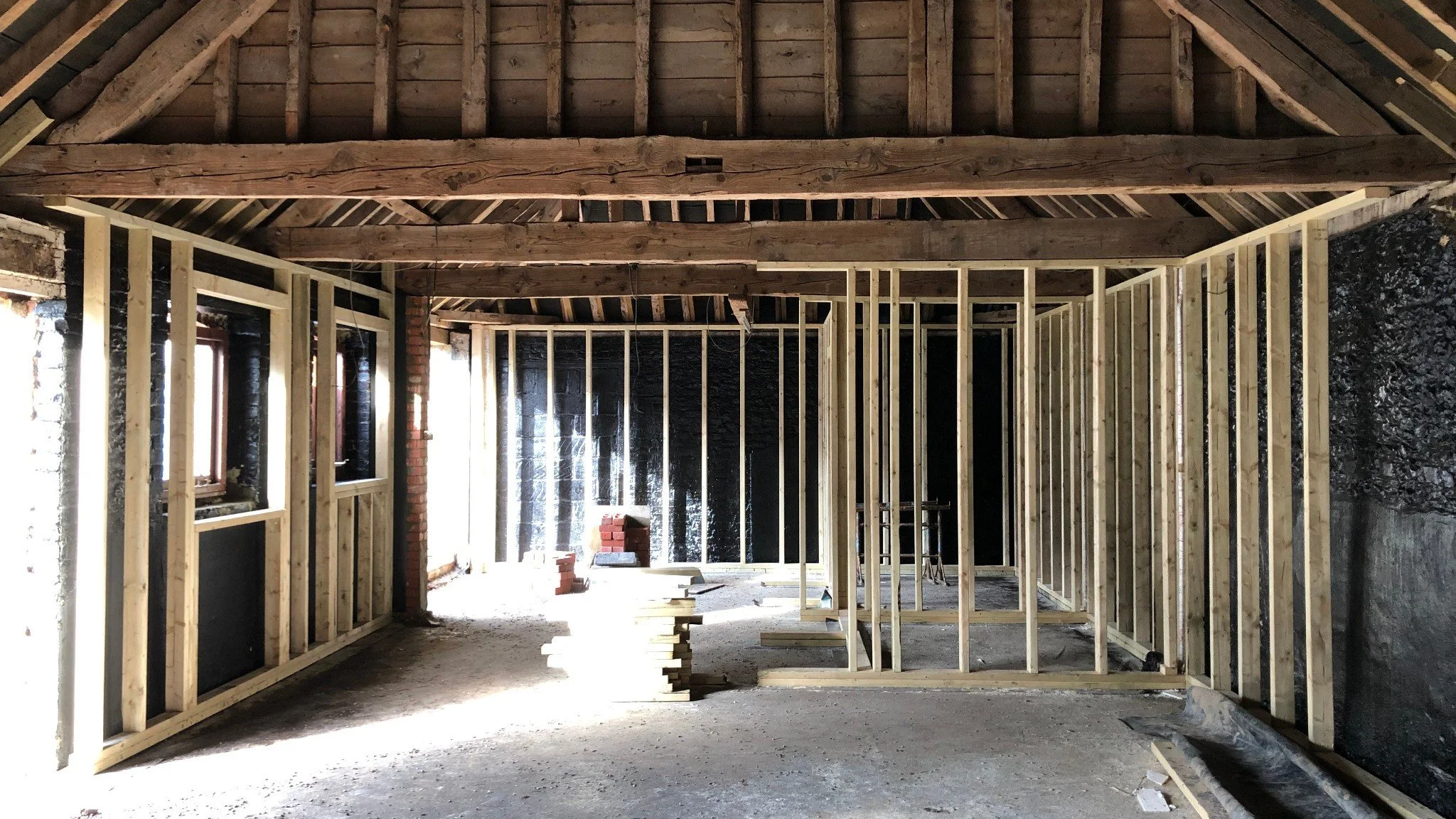 Internal timber framing during a barn conversion, showing exposed beams and new stud walls.