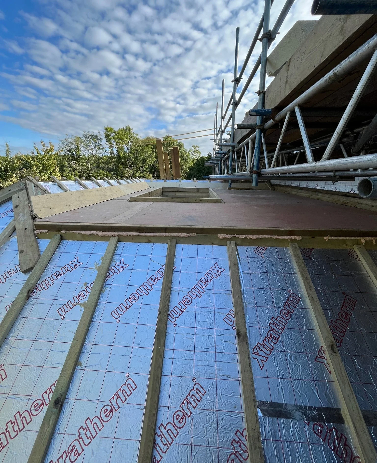 Roof construction detail at the Barcombe new build, showing insulation panels, timber battens and scaffolding.