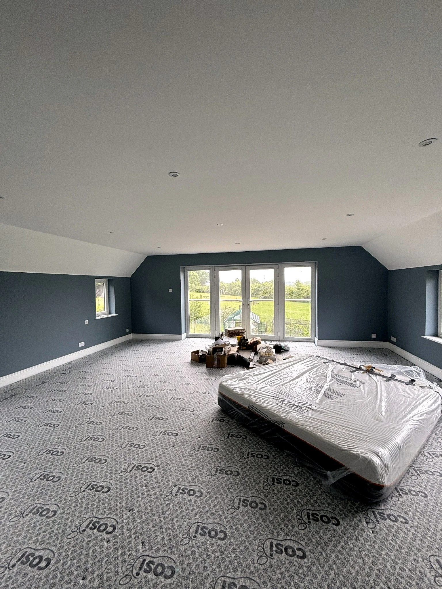 Completed bedroom with fitted carpet, roof slopes and large glazed doors in a Henfield home