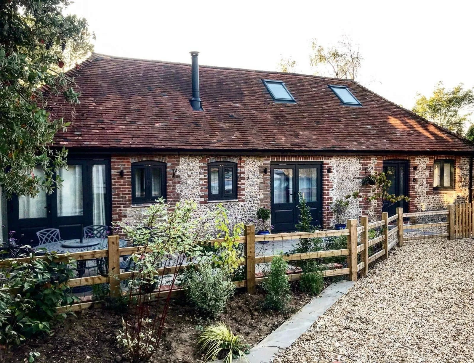 Completed Design & Build project in Sussex showing a renovated flint-and-brick property with dark-framed doors and rooflights