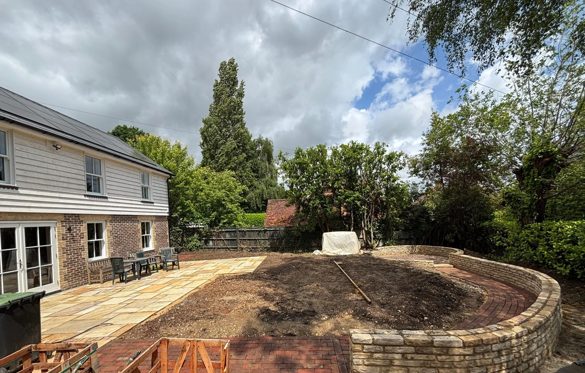 Rear elevation of a Lindfield property showing new patio installation, curved retaining wall and external landscaping works.