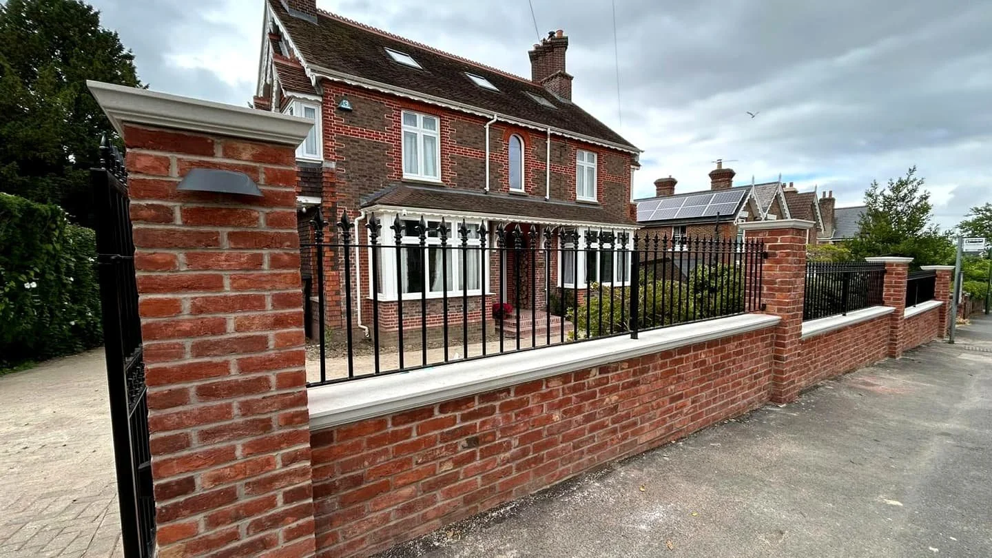 Completed design and build home with traditional red brick frontage and front boundary wall in Sussex