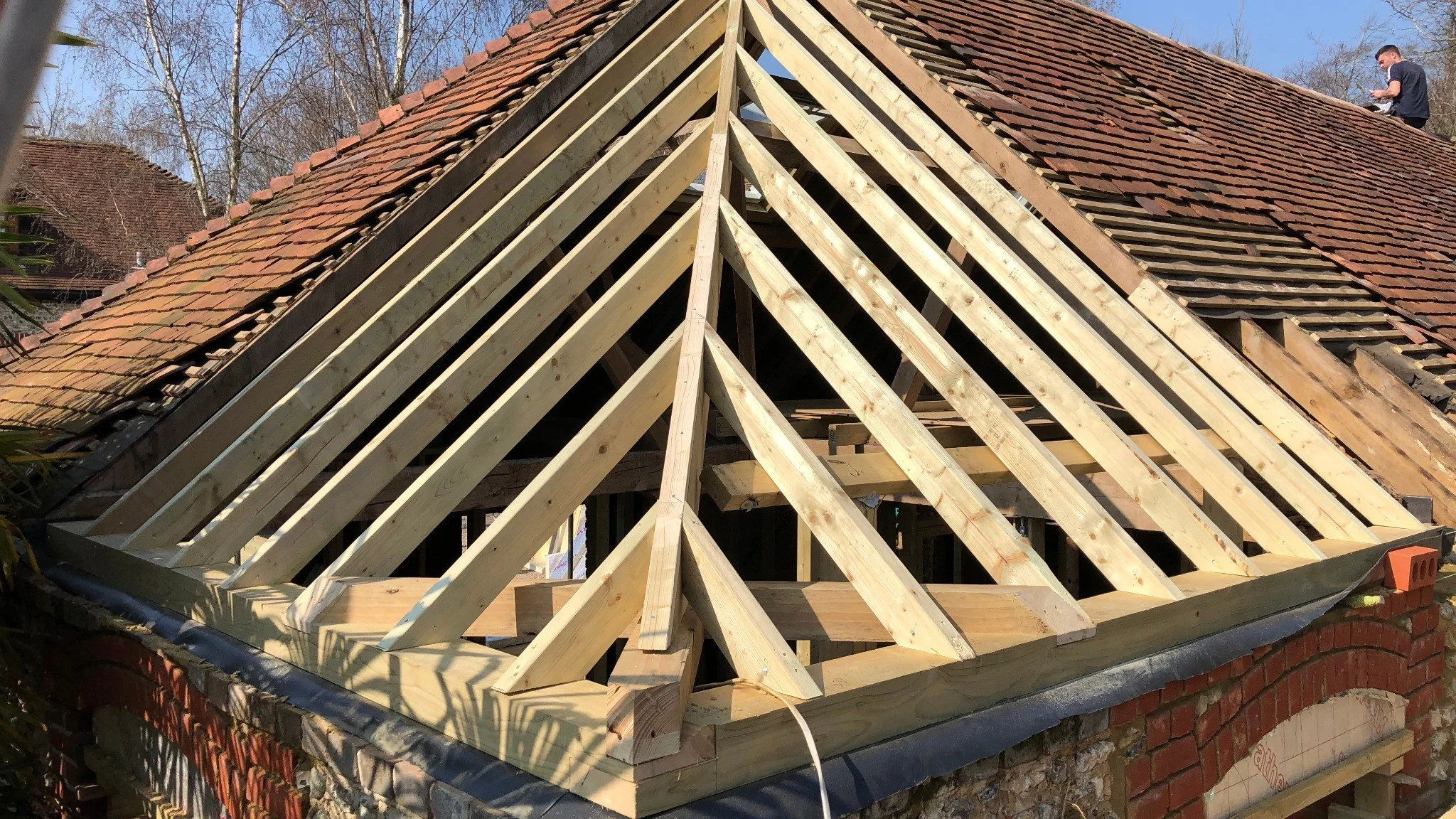 Roof structure under construction with new timber rafters installed during renovation work.