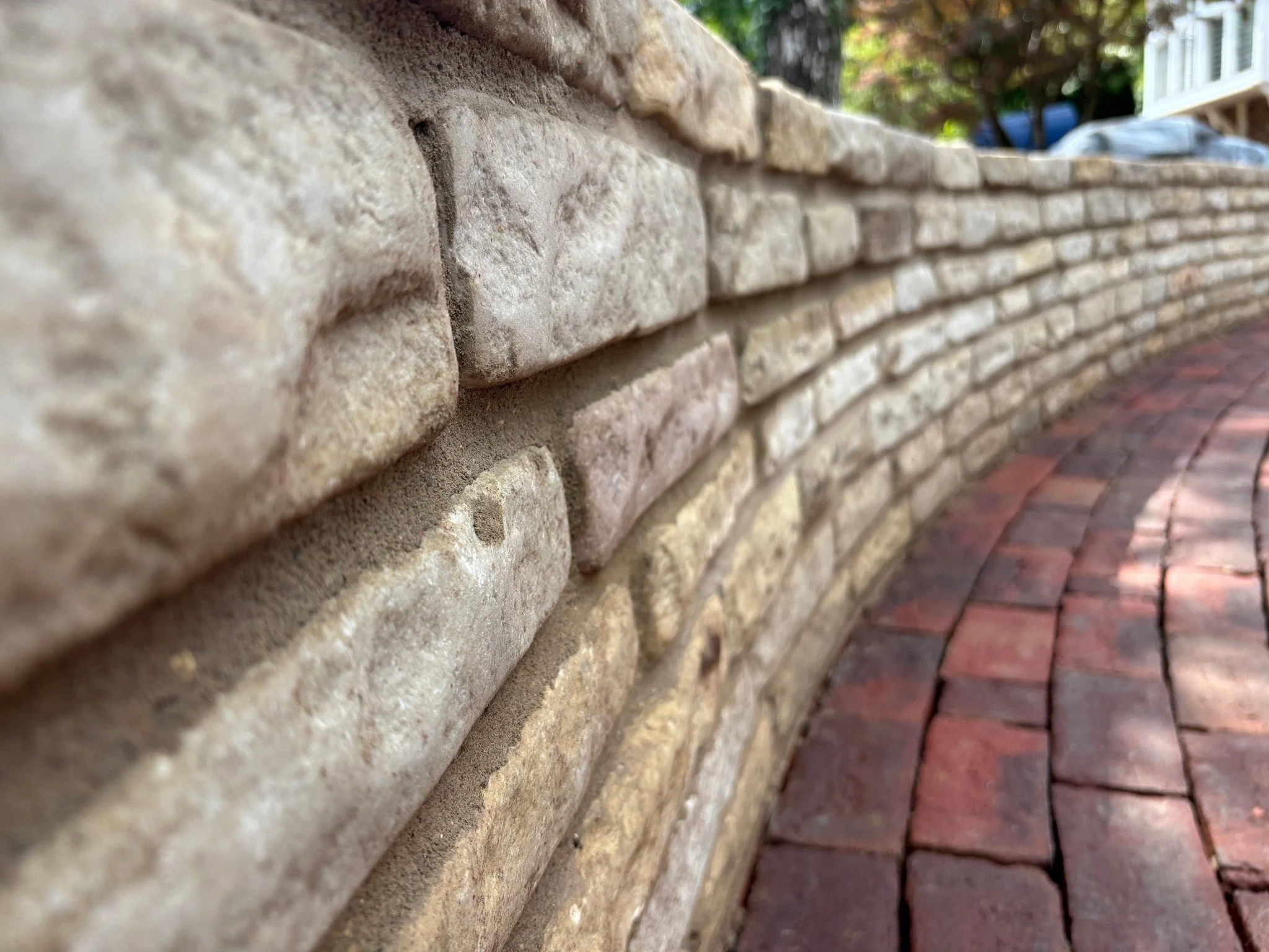 Close-up of curved stone wall and brick paving showing neat, precise workmanship.