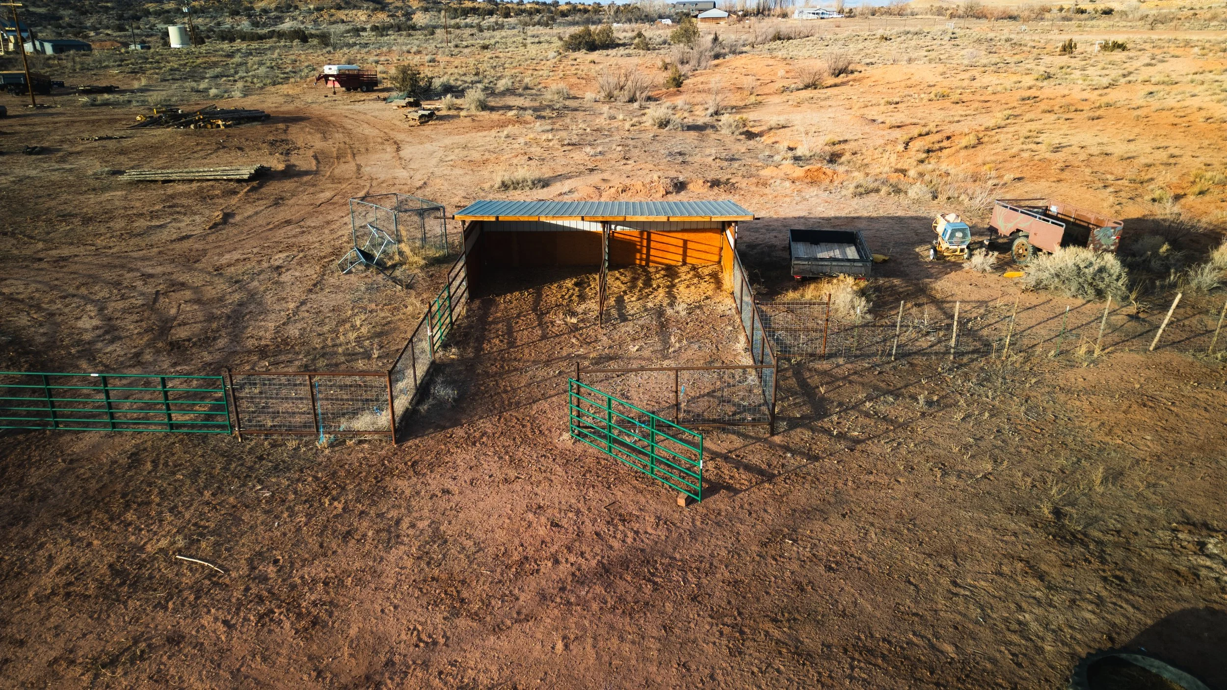 An aerial view of a fenced animal pen with a small shelter. Real estate drone photography and videography services in Roosevelt, Vernal, Uintah Basin, Utah, and nationwide.
