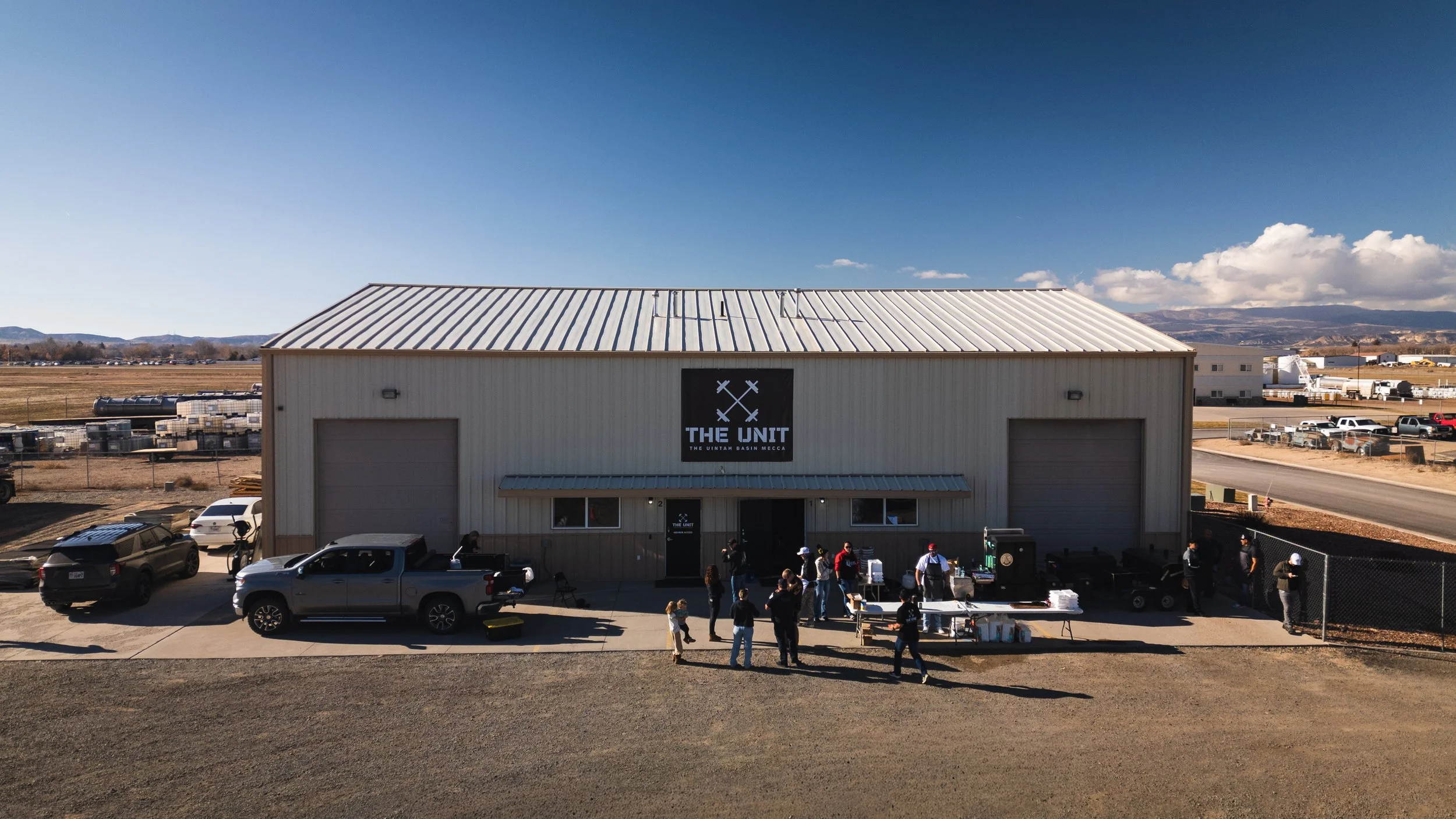 Drone photograph of a local gym, a large metal building with a sign that reads 'The Unit' and 'The Uintah Basin Mecca.' Drone photography and videography services in Roosevelt, Vernal, Uintah Basin, Utah, and nationwide.