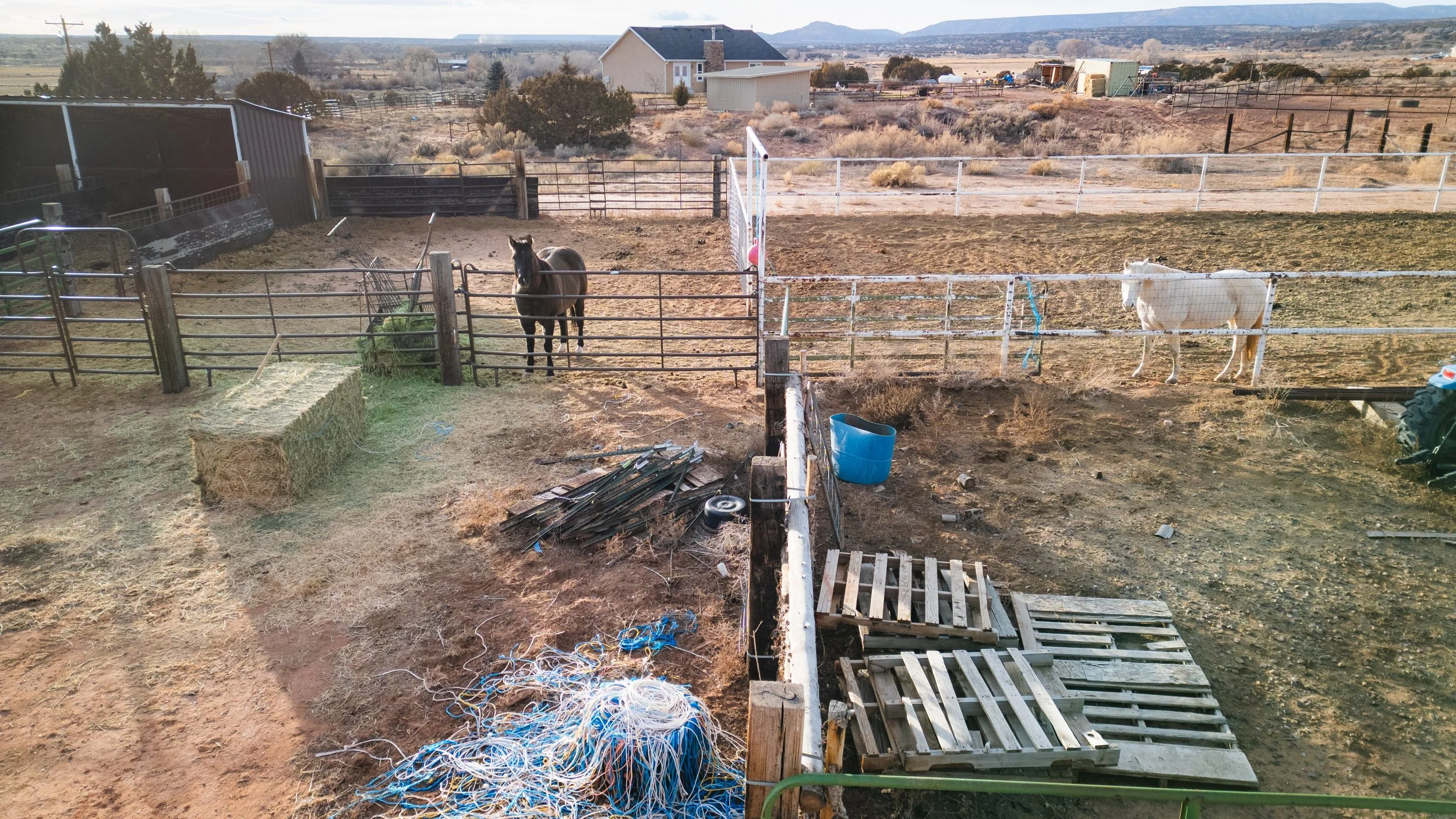 A farmyard with two horses in separate fenced paddocks. Real estate drone photography and videography services in Roosevelt, Vernal, Uintah Basin, Utah, and nationwide.