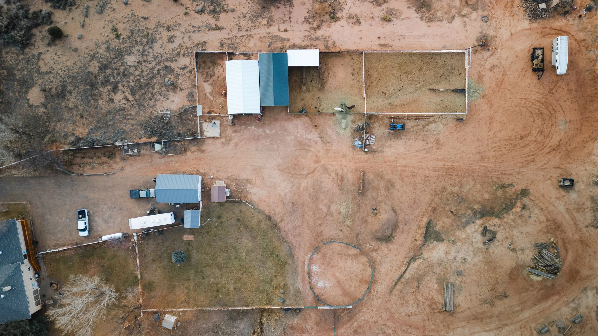 An aerial view of a construction site with fenced areas, dirt roads, construction equipment, and vehicles. Real estate drone photography and videography services in Roosevelt, Vernal, Uintah Basin, Utah, and nationwide.